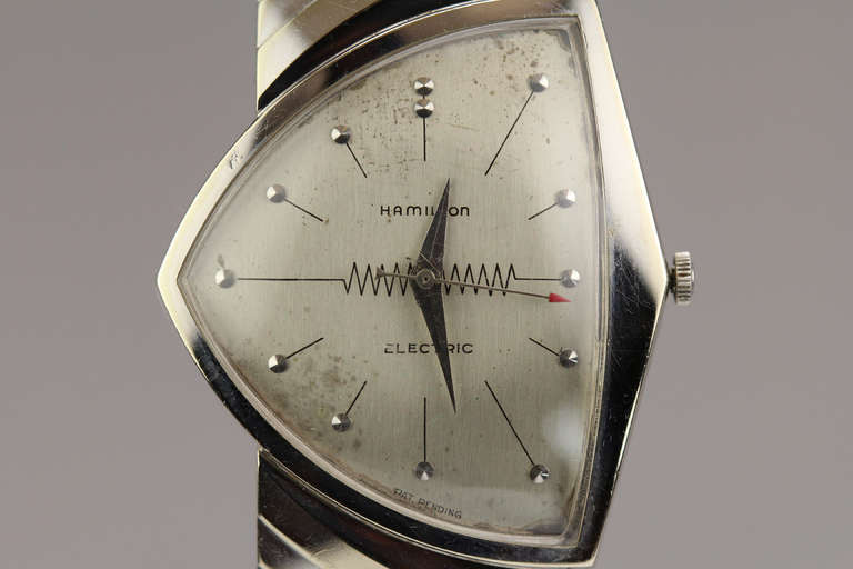 This is a rare Hamilton Ventura electric with an asymmetrical 14k white gold case, with snap back, stepped and hooded lugs, a silvered dial with applied markers, and the movement is electro-mechanical, cal. 500A.

The head has a 50mm overall