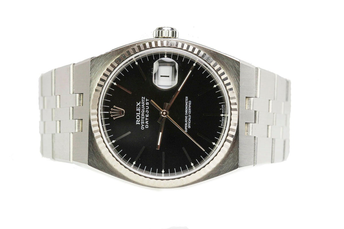 This is a mint Rolex stainless steel with white gold fluted bezel Oysterquartz Datejust manufactured in the year 2000. The dial is black with slash markers. This watch comes with its original Rolex papers, hang tags, manuals and service papers