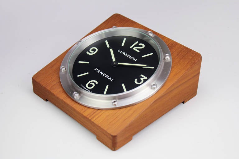 Panerai Luminor Pam 254 table clock in teak wood. This is a time-only clock, quartz movement with a black dial. This is an unused item and Includes outer box, inner box, battery, stickers instructions and undated warranty card. Measures