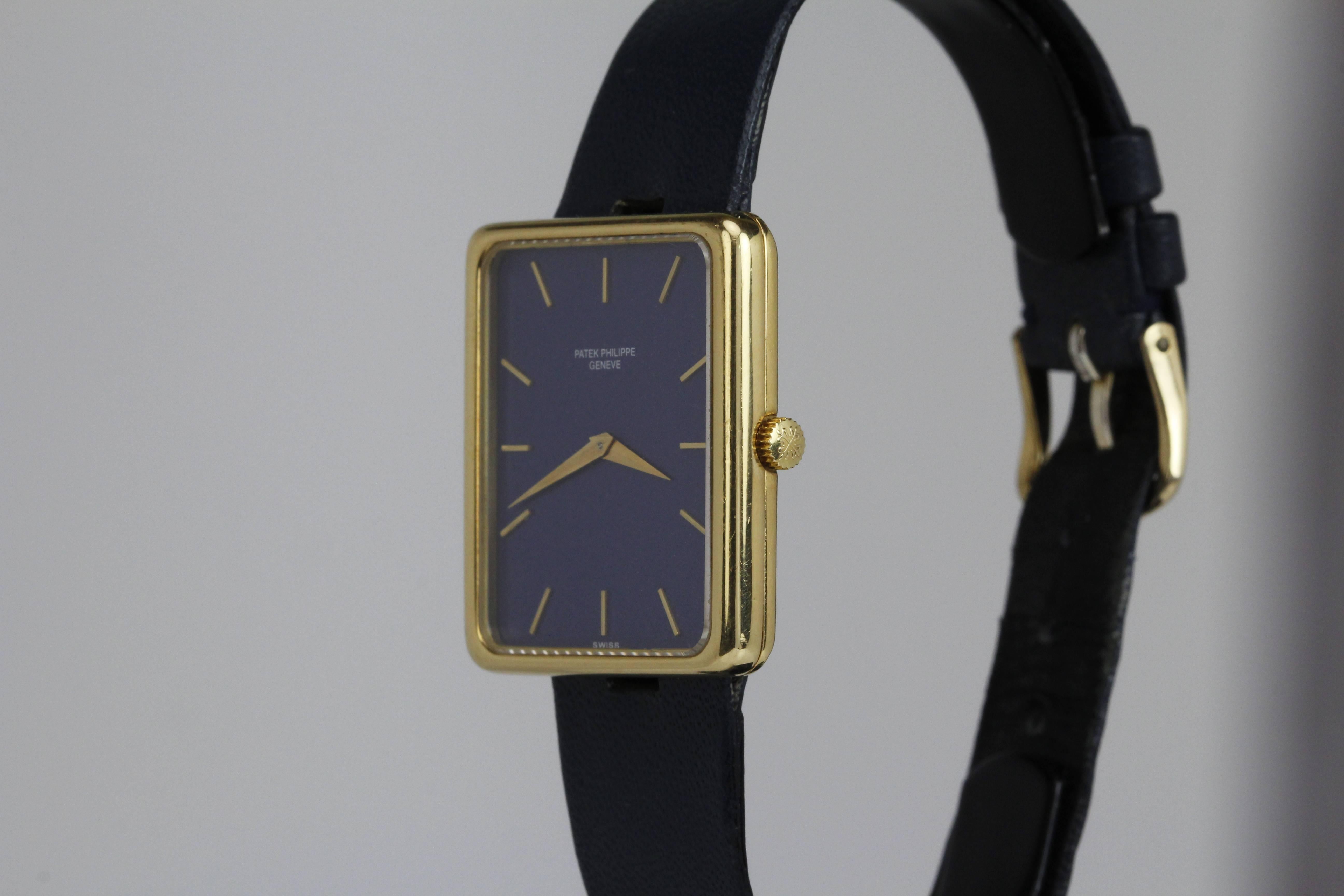 This is a classic Tank style wristwatch with an original metallic flake blue dial. The yellow gold case has hidden "T" bar lugs which hold the Patek Philippe leather strap. This is run with a caliber 16-250, 18-jewel manual wind movement.
