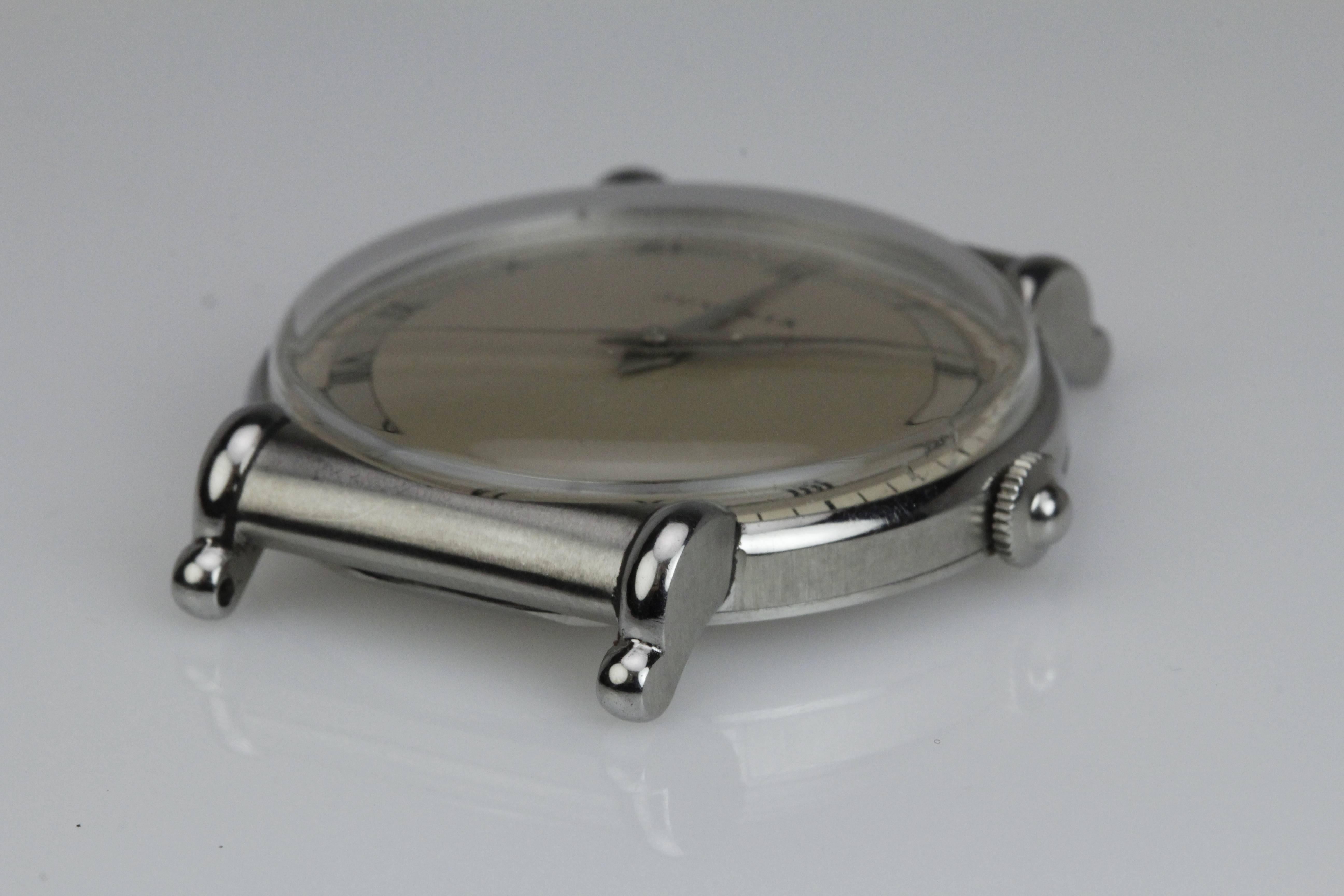 This is an elegant Calatrava style wristwatch by Juvenia from the 1940's. The 33mm stainless steel case has  partially hooded scroll lugs. This is a manual wind movement