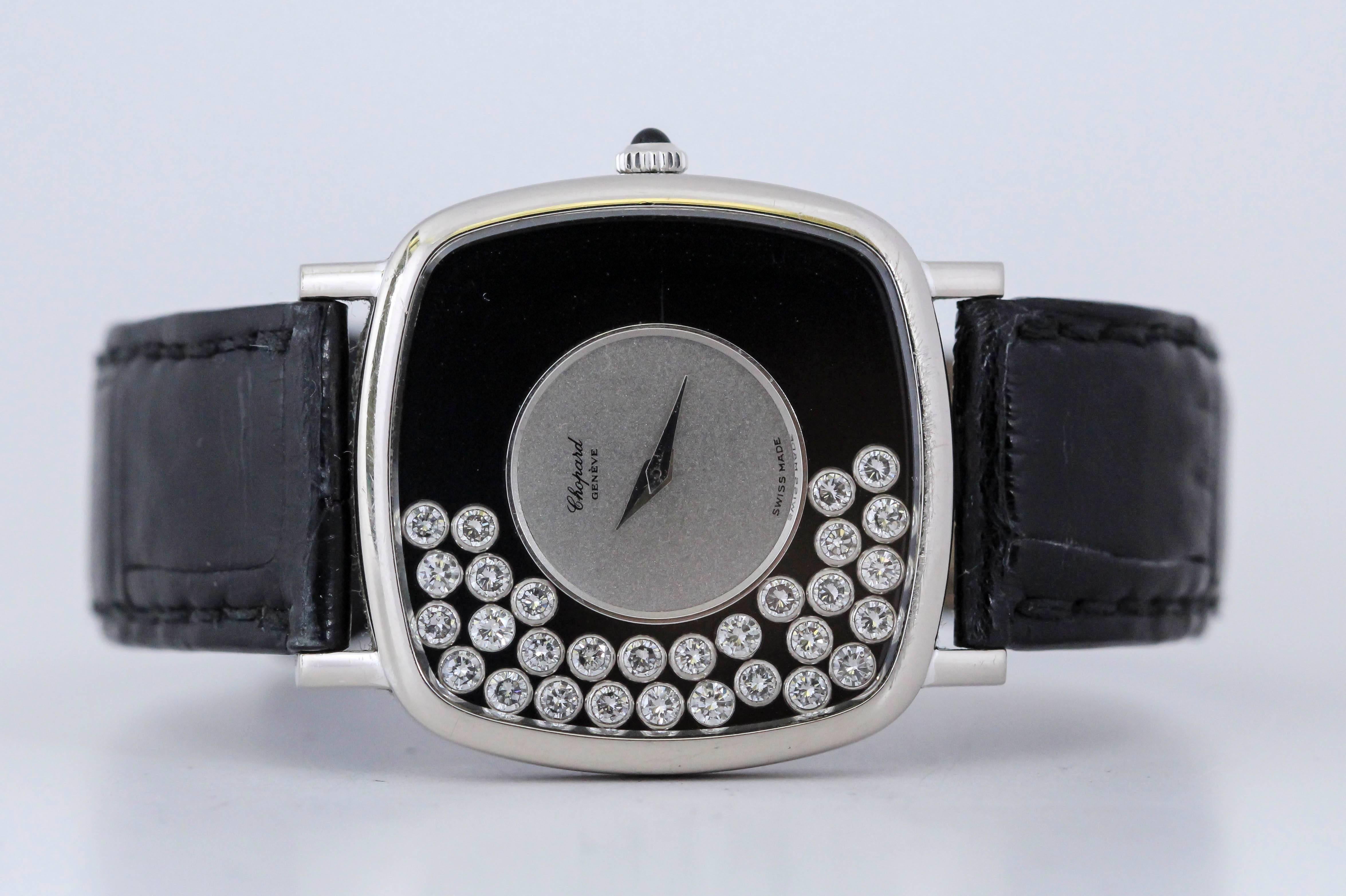 Chopard  Happy Diamonds reference 2106  with a cushion shaped 18k white gold case, black/silver dial with bezel set diamonds floating around, run by a manual wind movement and is on a modern Chopard leather strap and buckle. 