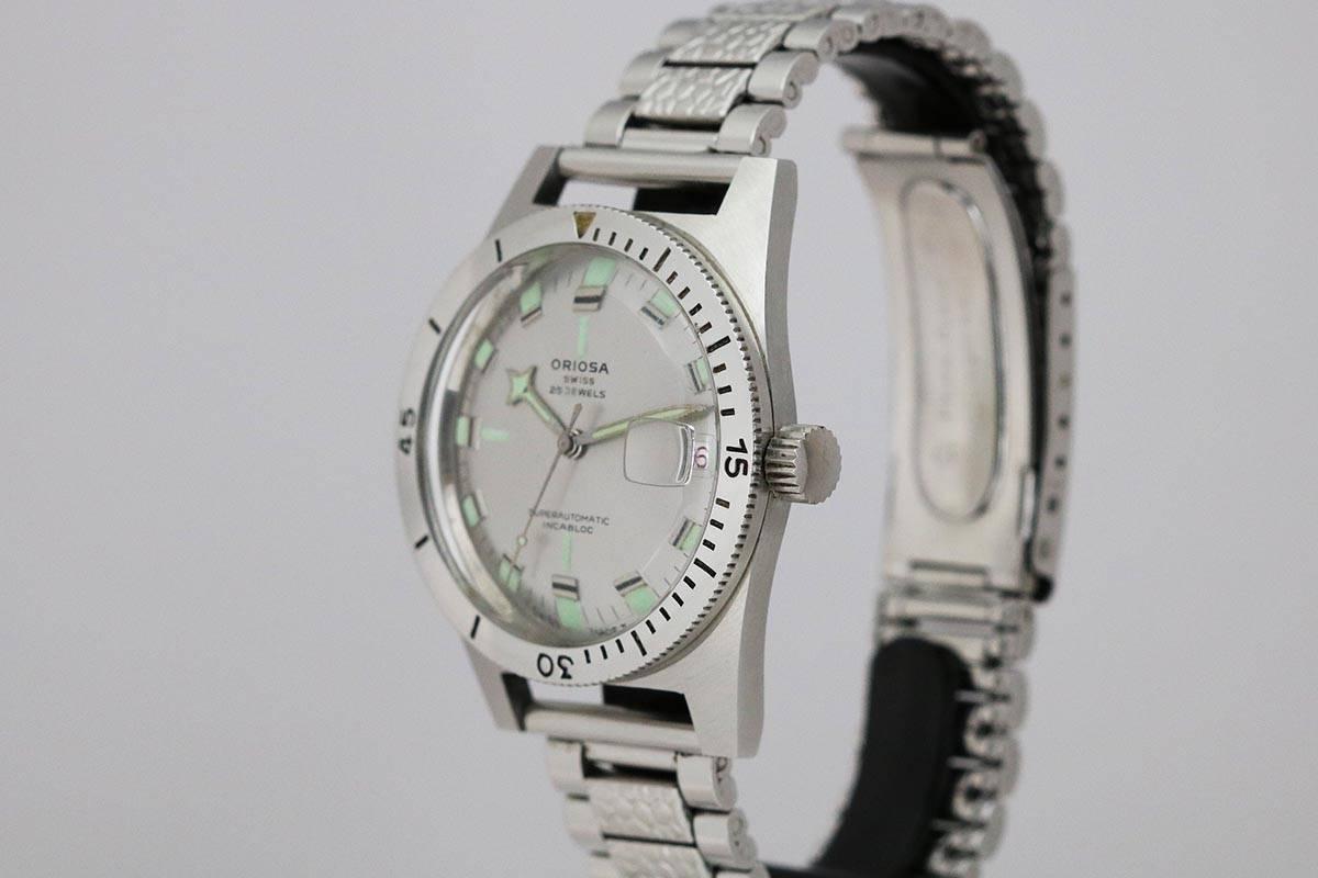Brand: Oriosa
Model: Diver's
Year: 1960s
Material: Stainless Steel
Dial Color: Silver with Luminous Markers and Date Aperture 
Dimensions: 39mm 
Watch Movement: Automatic
Bracelet/Strap: Stainless Steel Bracelet 
Box/Paper: No

