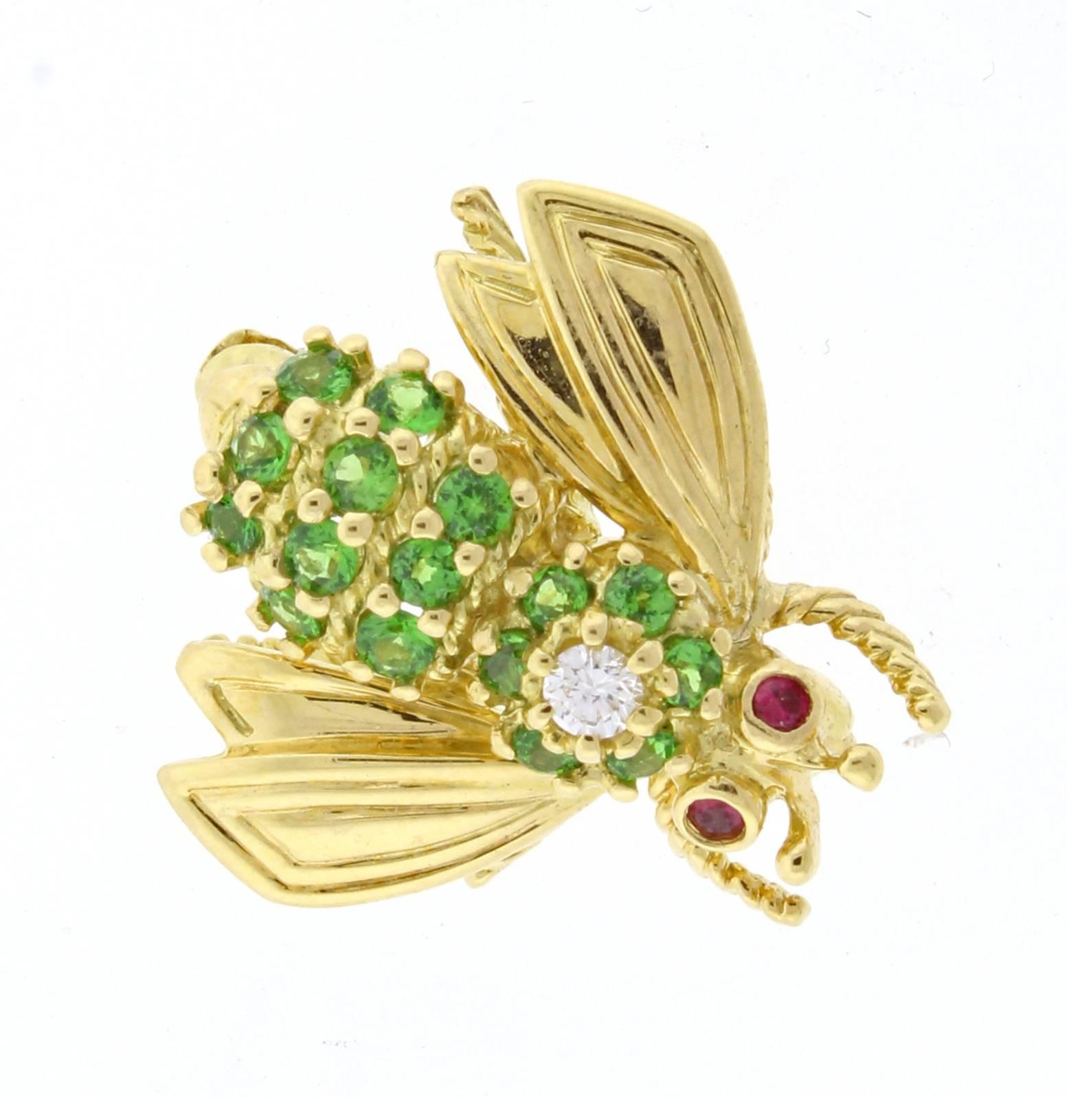 The 18 karat yellow gold Tiffany & Co. tsavorite and diamond bee brooch features 19 green tsavorite garnet weighing  .50 carats and a single brilliant round diamond weighing .06 carats. The brooch measures 3/4 of and an inch from wing to wing