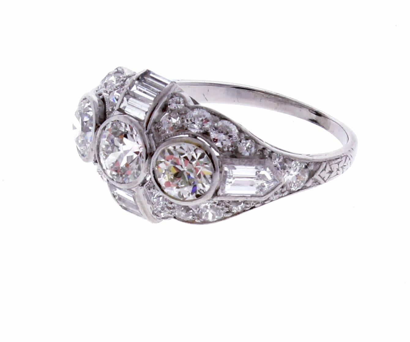 From the Belle Époque era, this well appointed three diamond ring .The handmade platinum ring features 3 old Europe cut diamonds weighing approximately 1.30 carats. The diamonds are H color and VS clarity.  The additional diamonds weigh