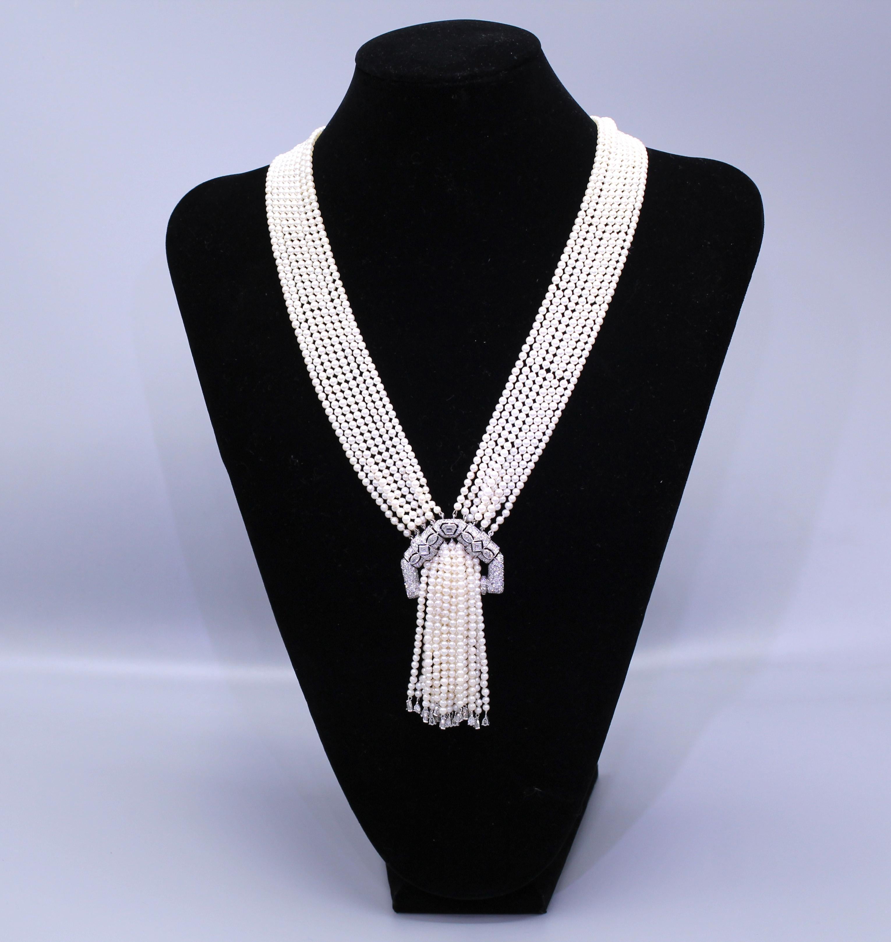 The necklace features an Art Deco platinum and diamond center section and 18 strands of 3.5mm pearls. The pearls appear to pass through the necklace each strand terminating with a pear shape diamond. The necklace is contemporary design by Bologa