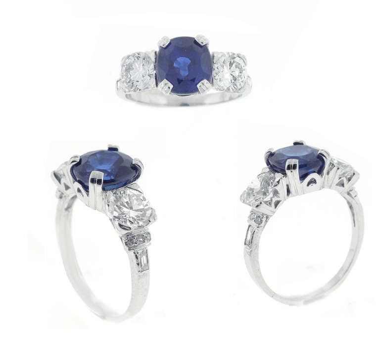 This antique blue sapphire and diamond three stone ring is platinum and features a center 3.05 carat sapphire. On either side of the sapphire are two old European cut diamonds with a total weight of 1.20 carats, color 