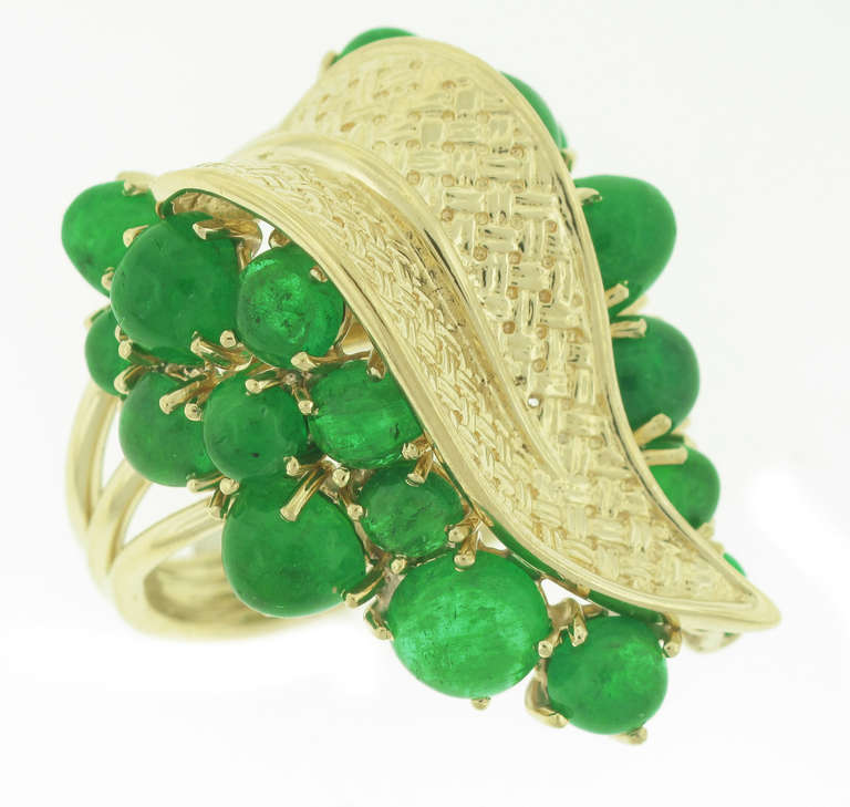 This Ruser 18-karat yellow gold and emerald ring features 25 cabochon emeralds with a total weight of 12 carats. The ring measures 1.25 inches in length and 1 inch in width. 

The ring is a size 6 and can be sized.