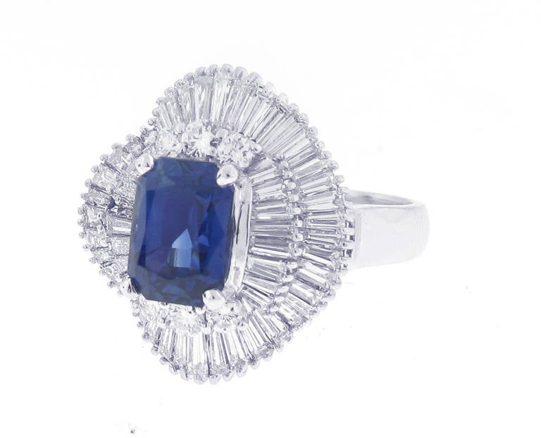 This Sapphire and Diamond cocktail ring features 1 stunning emerald cut Ceylon blue sapphire 3.37 carats. The sapphire is two wavey rows of 64 baguette diamonds with a total weight of 2.62 carats. The ring is 18 karat white gold, is a size 6.75 and
