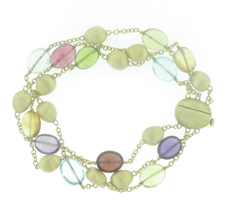 This Marco Bicego Multi-Gemstone Bracelet is in 18 karat yellow gold and features a multitude of semi-precious stones including: topaz, amethyst, citrine, etc. There are three separate strands of gold chain and gemstones that make up this playful