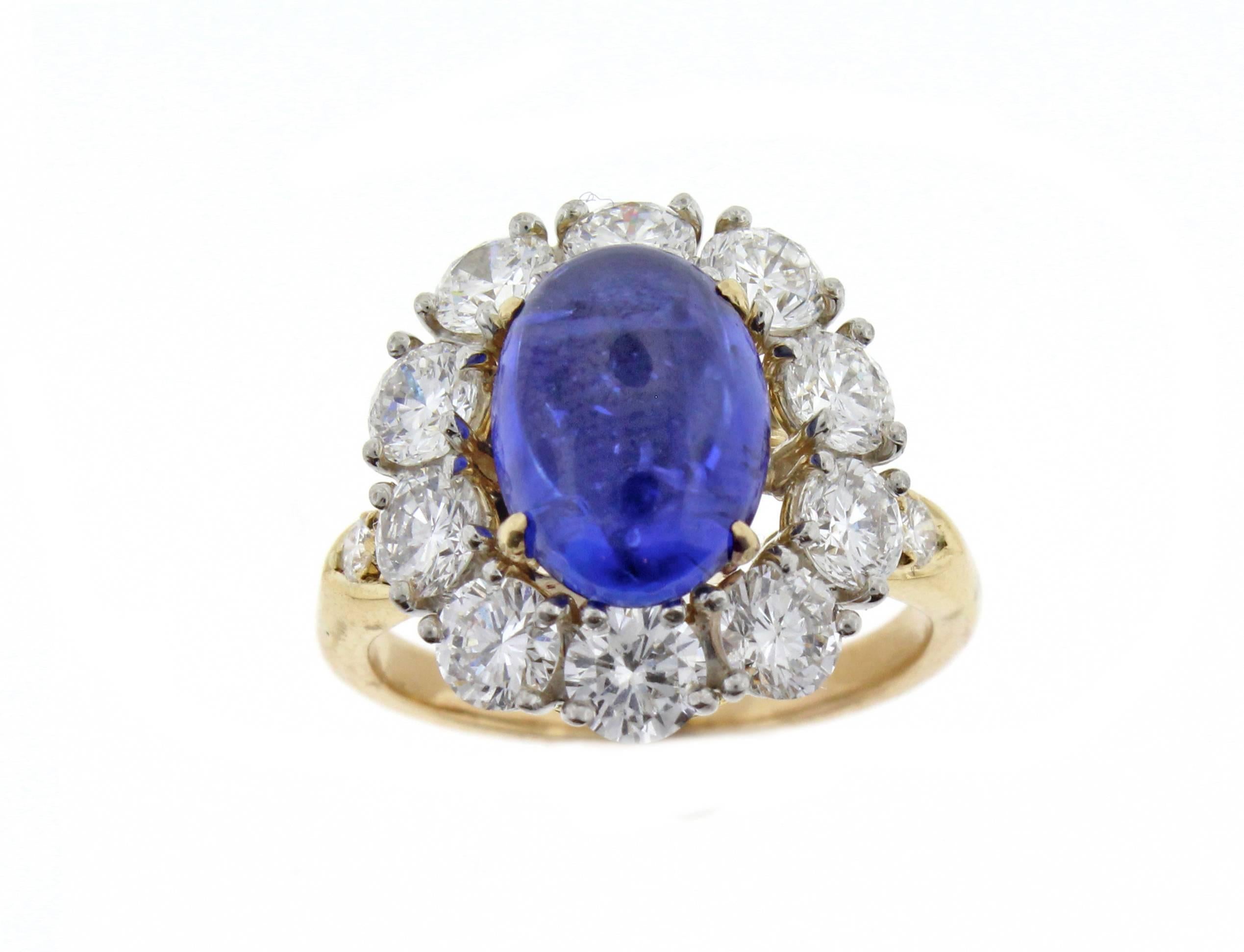 From the workshops of Van Cleef and Arpels, a sapphire and diamond cluster ring. Comprised of a center cabochon sapphire weighing 4.16 carats and 16 brilliant cut diamonds weighing 2.21 carats. set in 18 karat gold and platinum. Signed Van Cleef and