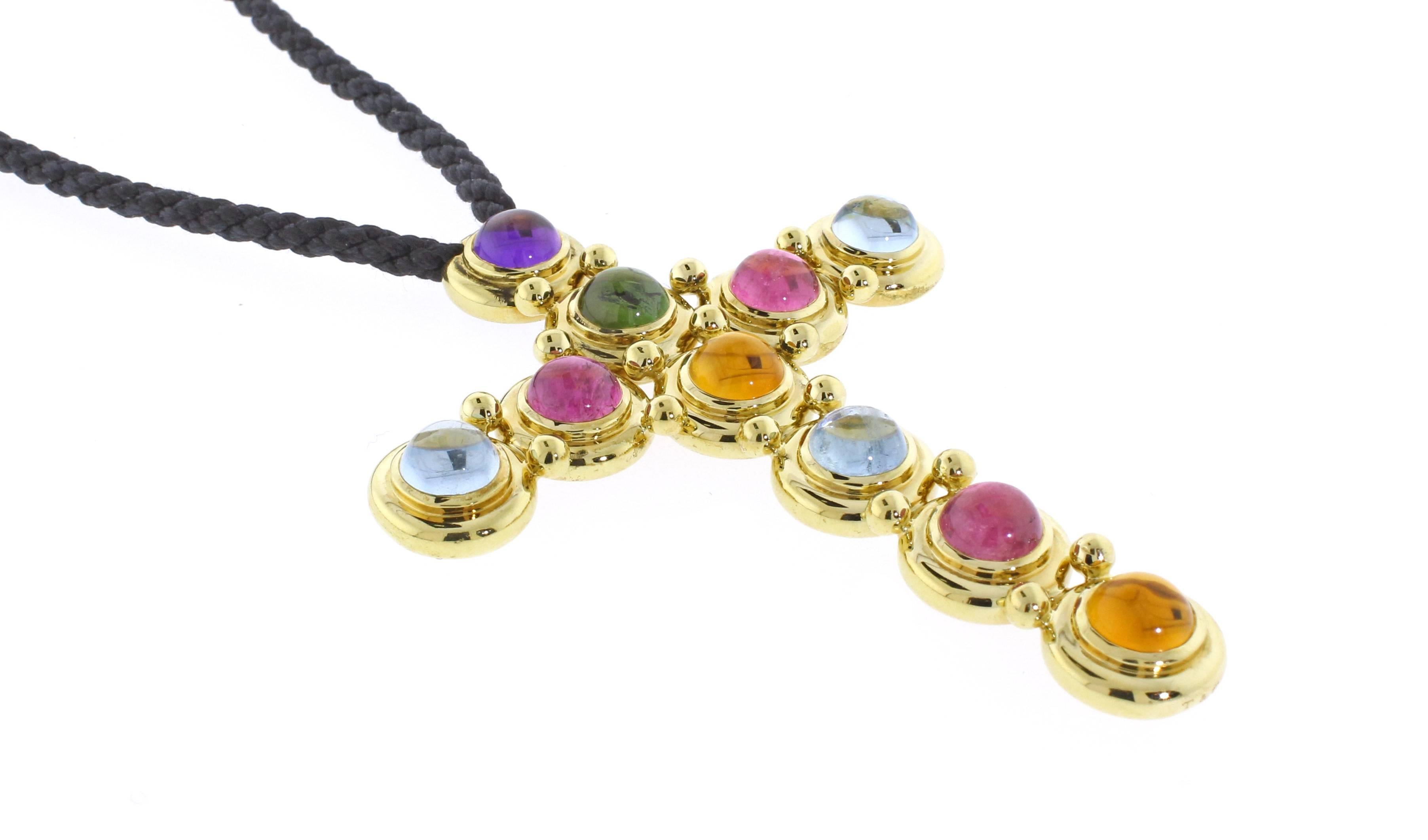 From Paloma Picasso an 18 karat gold cross set with 10 cabochon gemstones. Measuring 2 1/2 by 3 inches the cross makes a colorful statement. 30 inch black silk cord ties ties any length

8mm Cabochon Aquamarines, Amethyst, Tourmalines and Citrine 