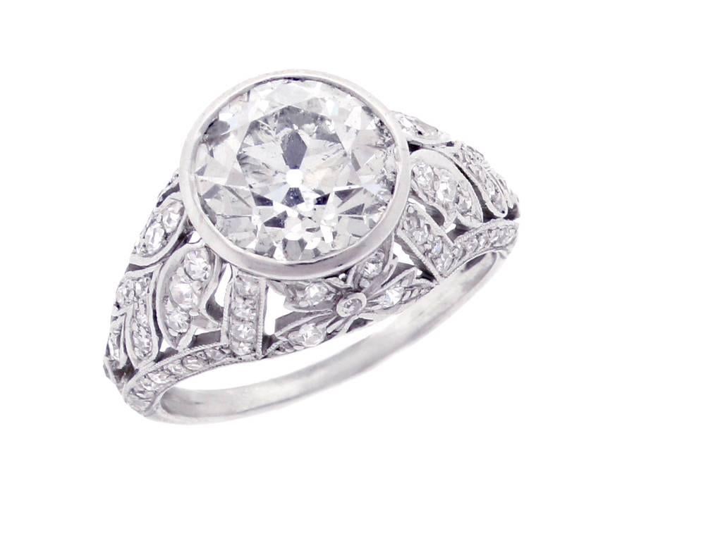 This diamond ring is an exceptional example of Edwardian design and craftsmanship. The ring features a center old european cut diamond weighing  3.10 carats The diamond is I color and SI2/I1 clarity. The handmade  setting is comprised of 76 round