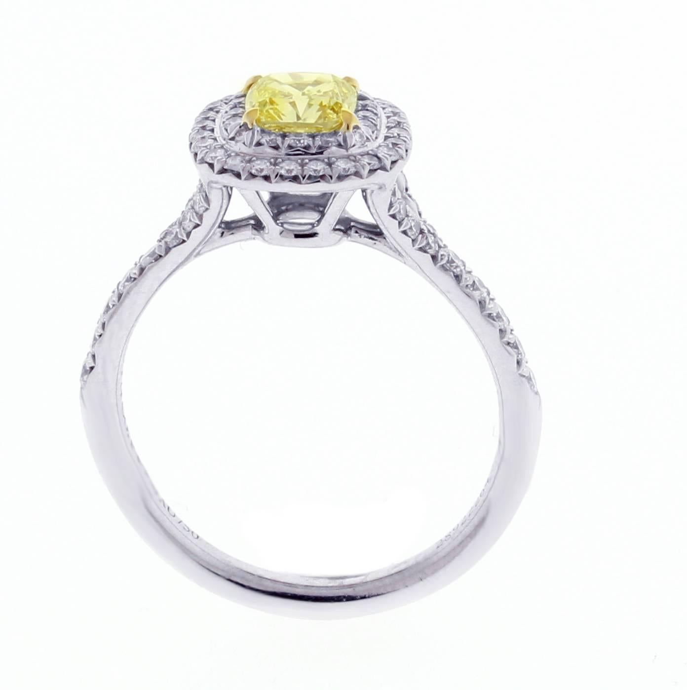 A riveting cushion cut Tiffany Yellow Diamond smolders with the intensity of sunlight.  The Fancy Intense Yellow  cushion cut diamond weighs .66 carats, with round brilliant white diamonds, weighing .36 carats. Ring in platinum and 18k gold, size,