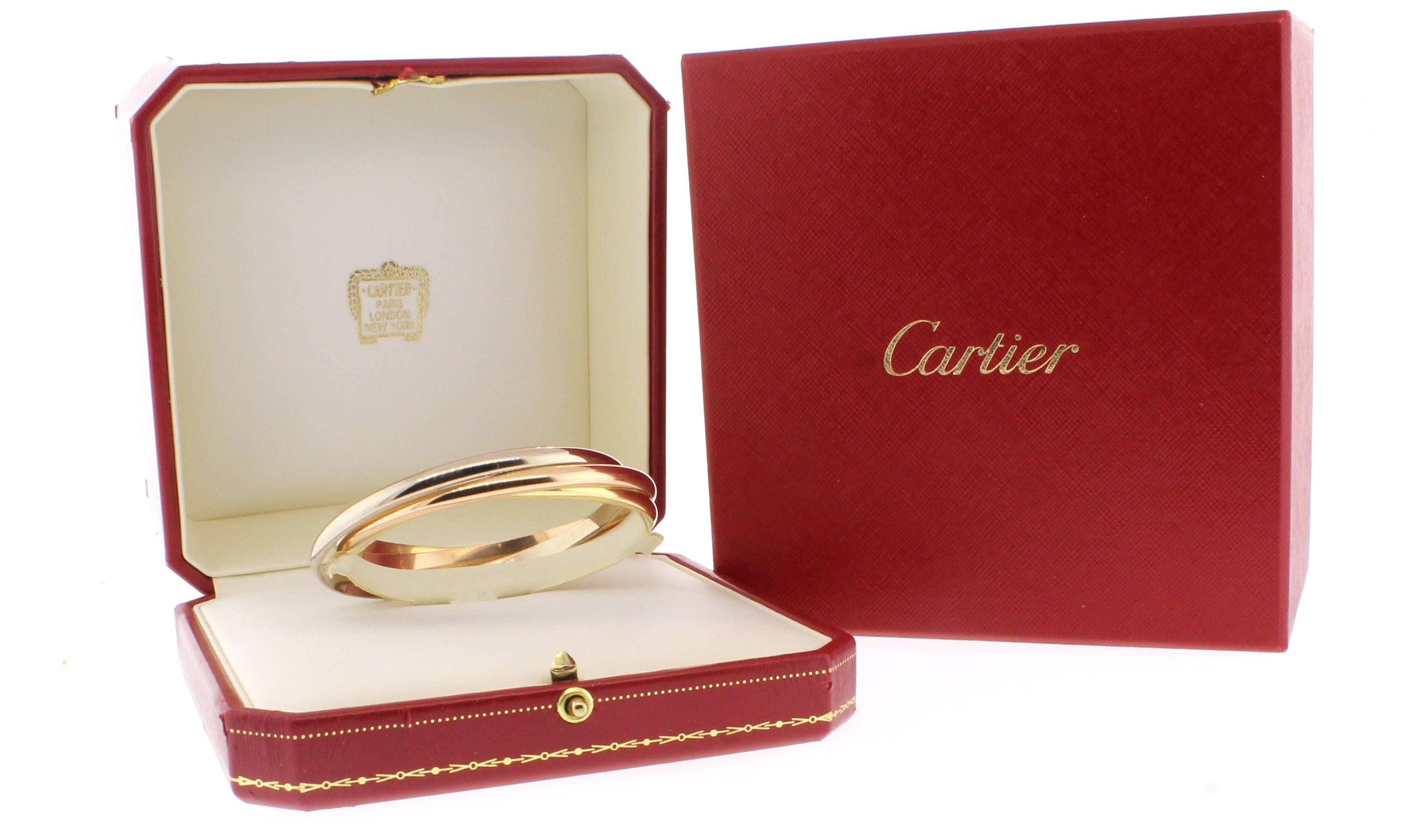 Three bands. Three colors. Pink gold, yellow gold and white gold, intertwined in a display of mystery and harmony. This iconic bangle from Cartier features three   18 karat 4.5mm bangles, encircled for all time. 60.2 grams. Original box, certificate