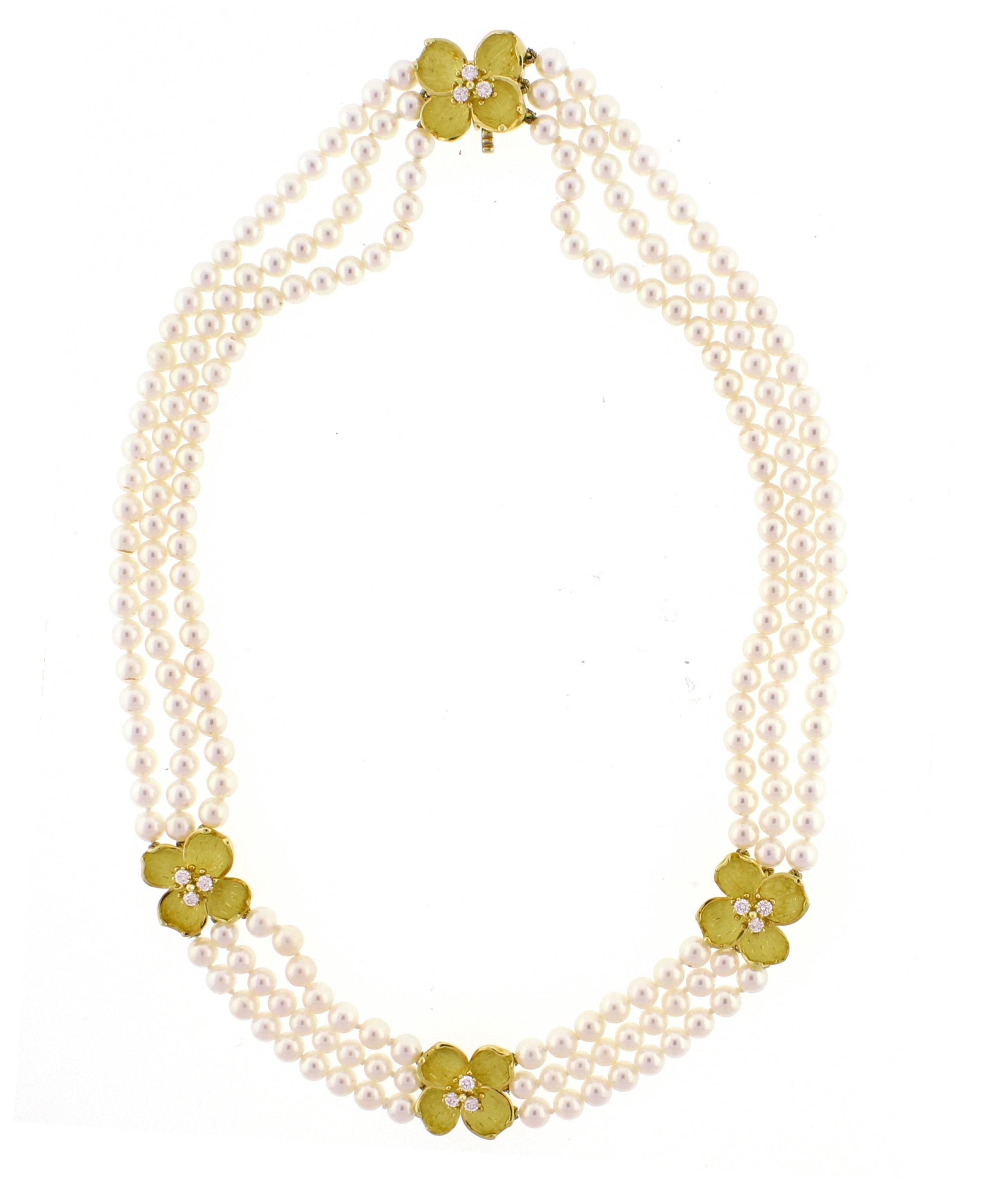 From Tiffany & Co. a pearl necklace and gold  necklace. The necklace is comprised of three strands of 4.5-5mm cultured pearls. Three 18 karat yellow  gold and diamond dogwood motifs highlight the necklace along with a matching clasp. 12 briiliant