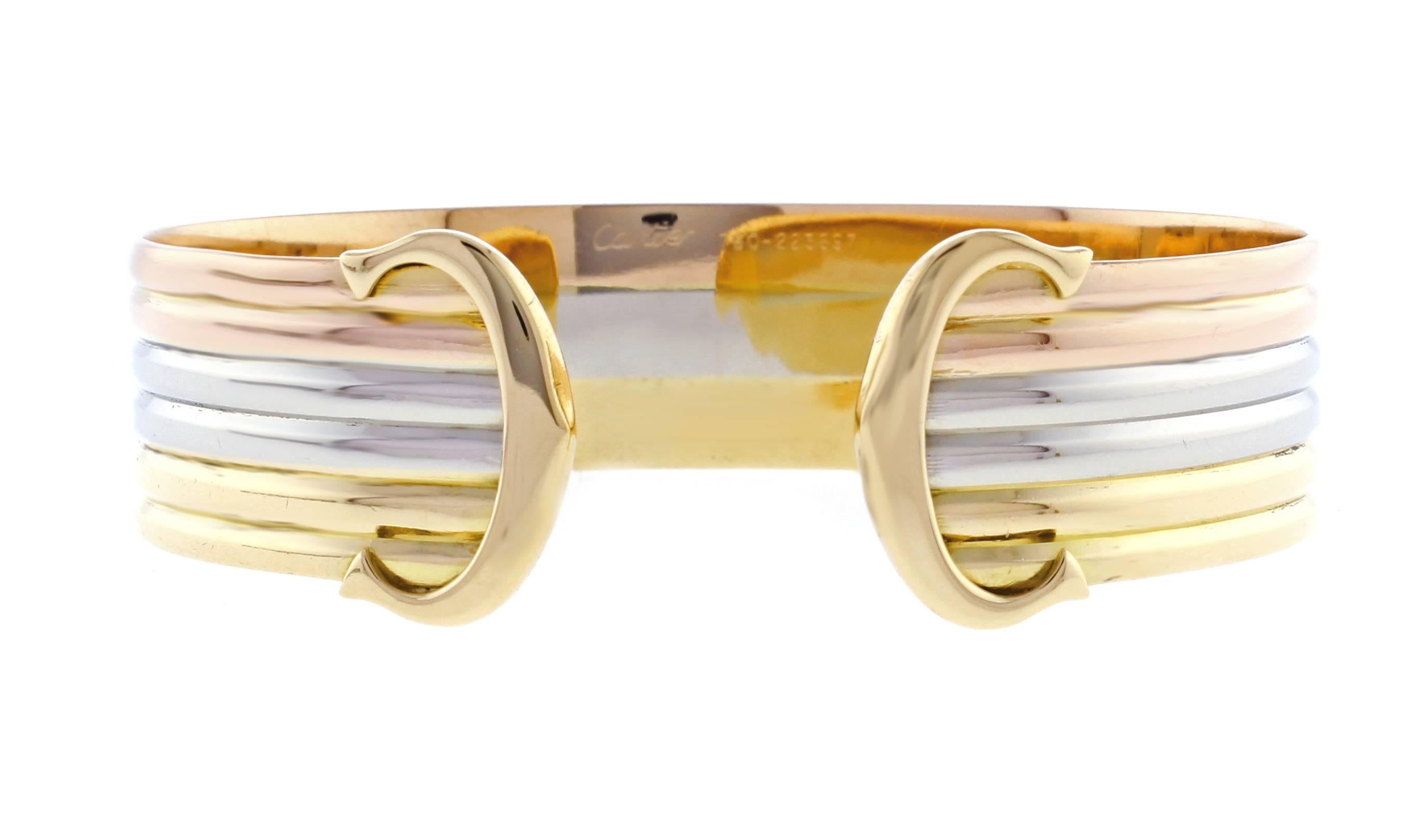 From Cartier, their iconic double C de Cartier decor trinity bracelet. Crafted from white yellow and pink 18 Karat gold. 5/8 of an inch wide, medium (17) size 