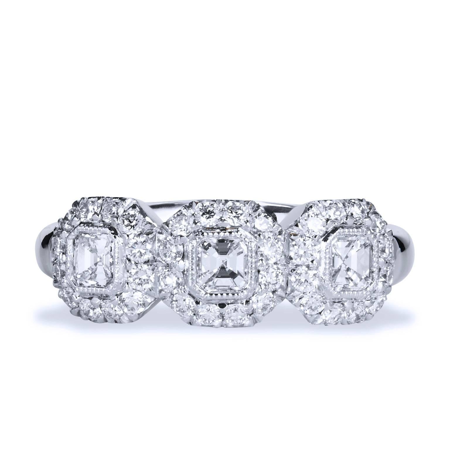 This stylish three stone ring Designed by H features 3 square Emerald Cut diamonds weighting 0.47cts F/G VS1 and 0.44ct pave-set diamonds surrounding the three emerald cut diamonds. This 18kt White gold with palladium ring size 6 1/4.