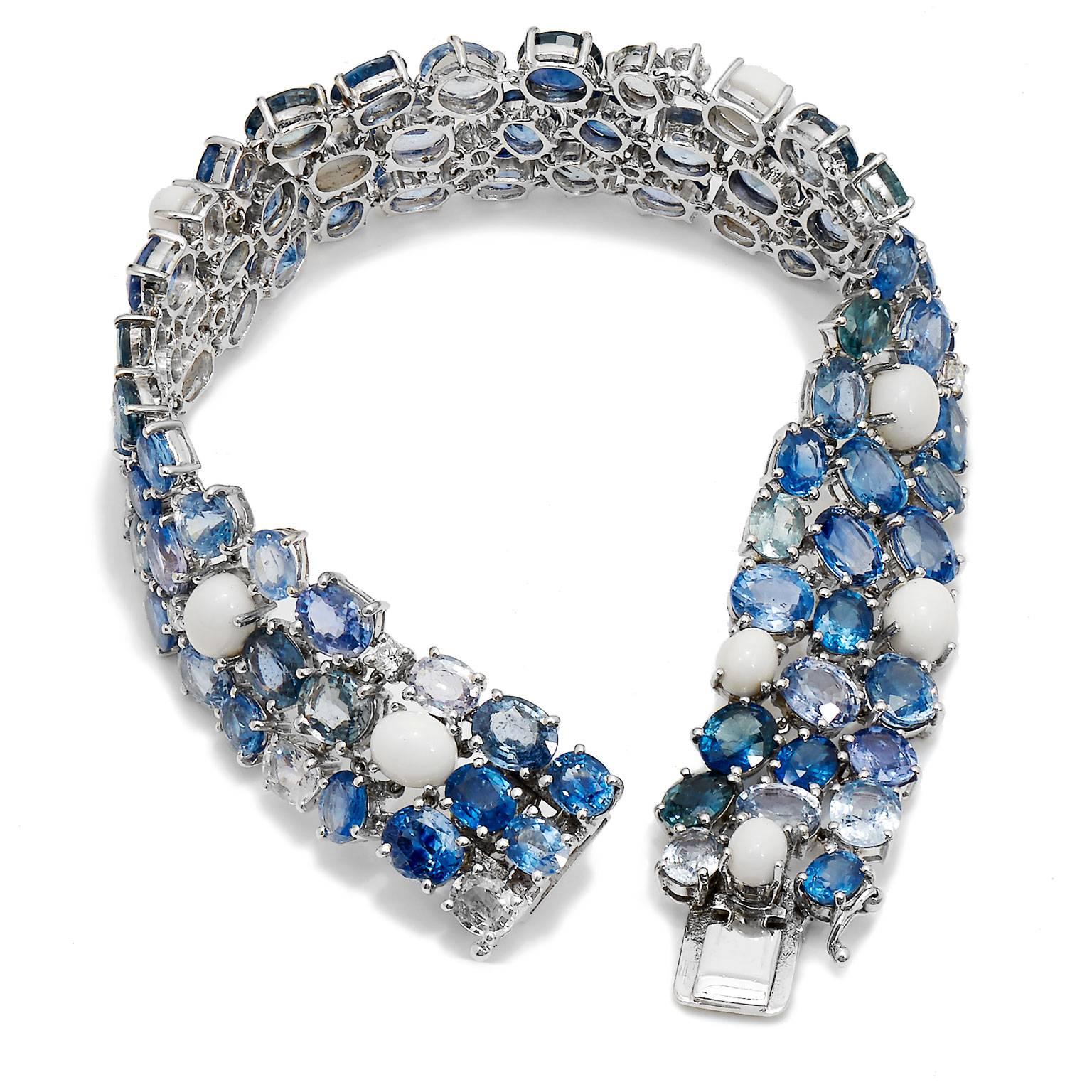 Paint the sky with varying hues of blue sapphires in this 18 kt white gold bracelet. 0.16 ct diamonds punctuate the vast expanse of 49.89 ct of multi-color blue sapphires, while delicate and pristine white coral float like clouds. Elevate her style
