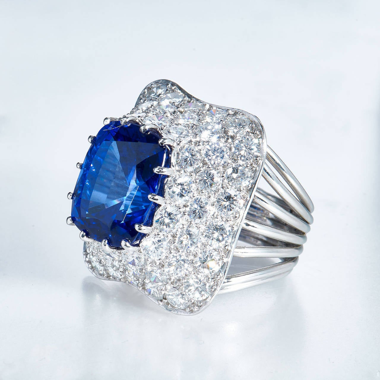 Emulating the natural beauty of the moon and stars, this 1970's platinum cocktail ring features a luscious blue 10.18 carat cushion-cut tanzanite enclosed by a pyramid of brilliant-cut, round, white diamonds graded EF VS1 and totaling 54 stones with