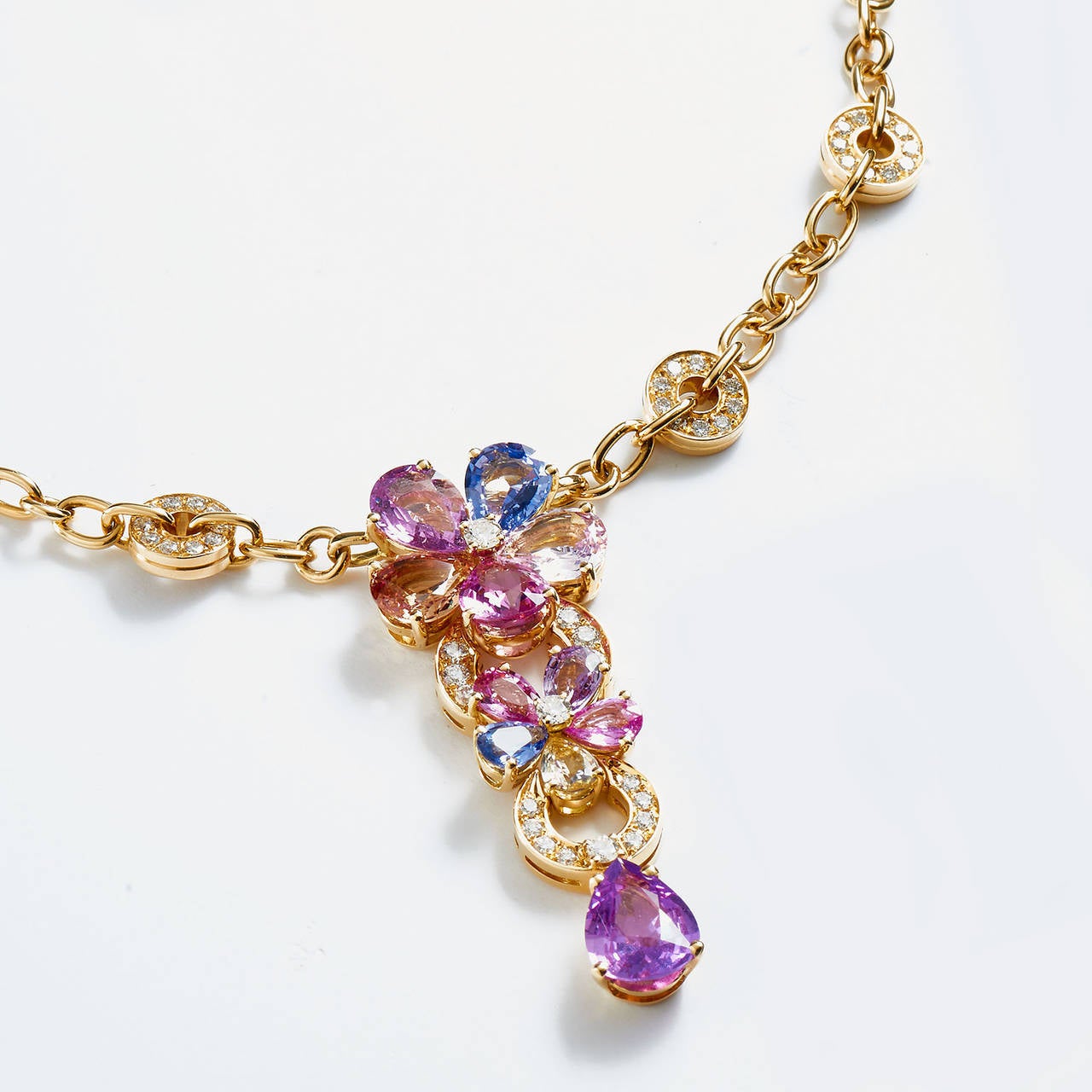 This vibrant 18K yellow gold Bvlgari piece features a rainbow of lavish natural sapphires creating a kaleidoscope of color. Ten multicolor pear shape sapphires form two central flowers that drop from the chain to elegantly lay on the chest with a