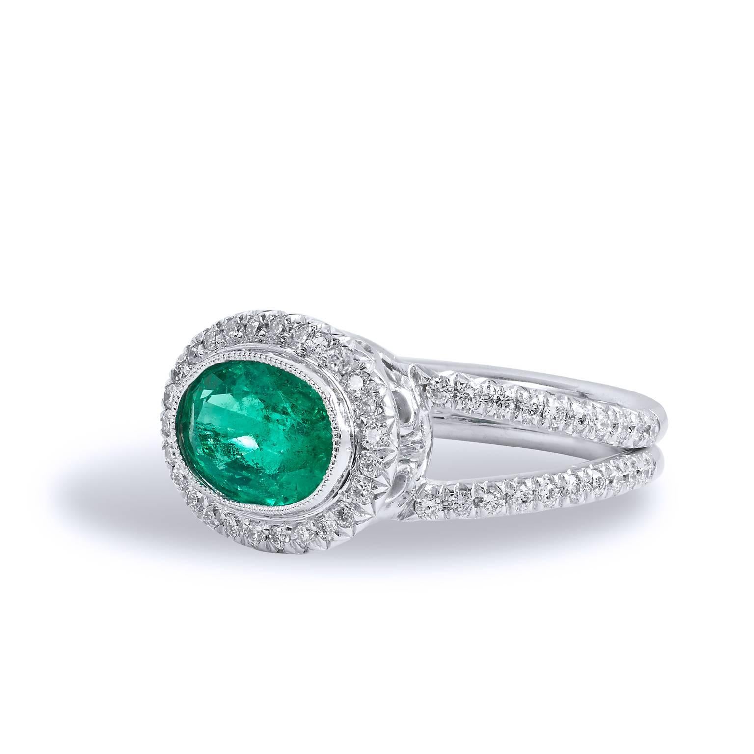 18kt white palladium forms the base for this luscious handmade Emerald and Diamond ring. Taking center stage is a 1.84 carat oval cut Zambian Emerald displaying a vivid green hue. Clutching the center gemstone and trailing down the split shank are