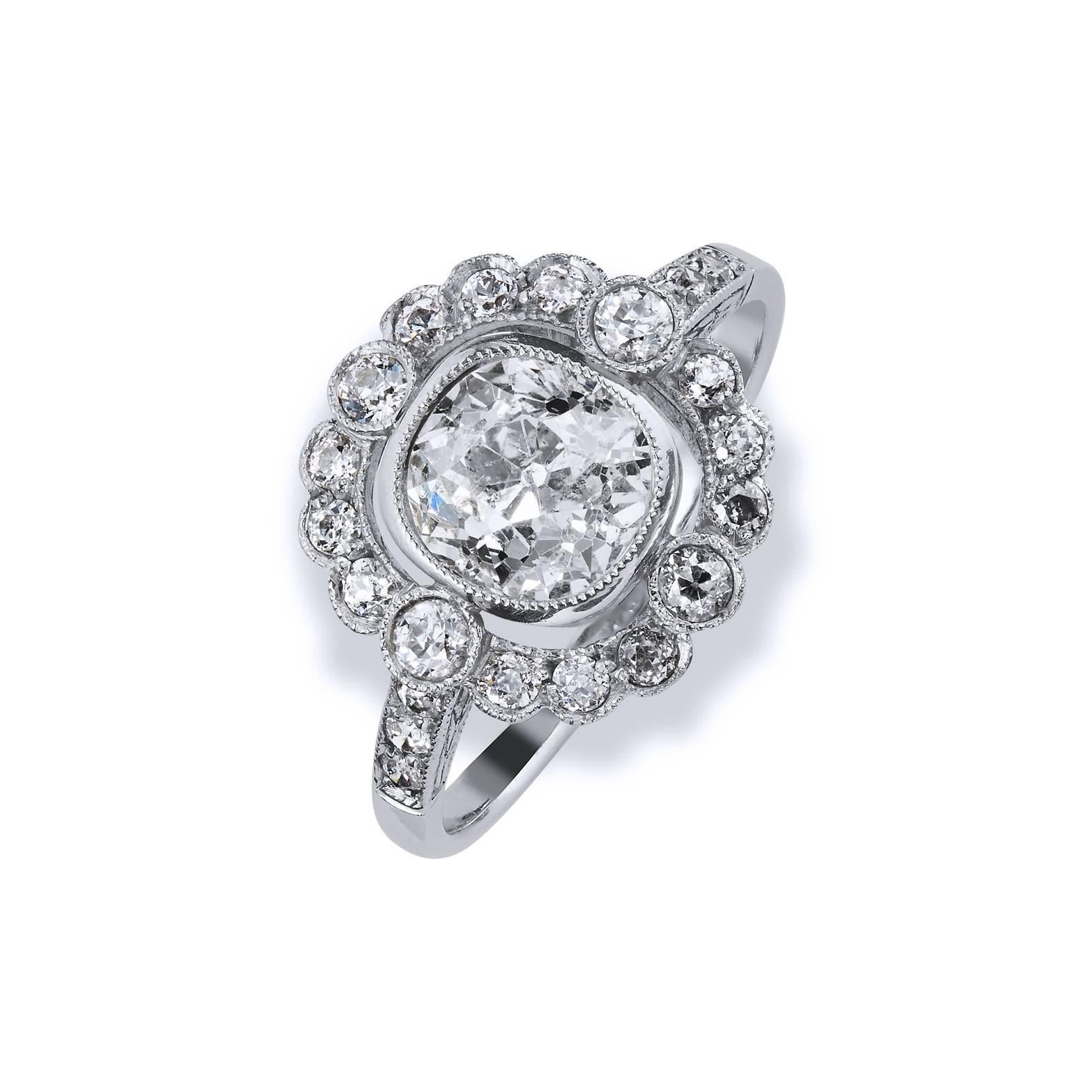 Crafted in platinum, this Art Deco style engagement ring features a 1.39ct old min cut center diamond graded H/I color and I2 clarity. Approximately .55cts’ of bezel set diamonds caress the scintillating center stone and trail down the shank for a