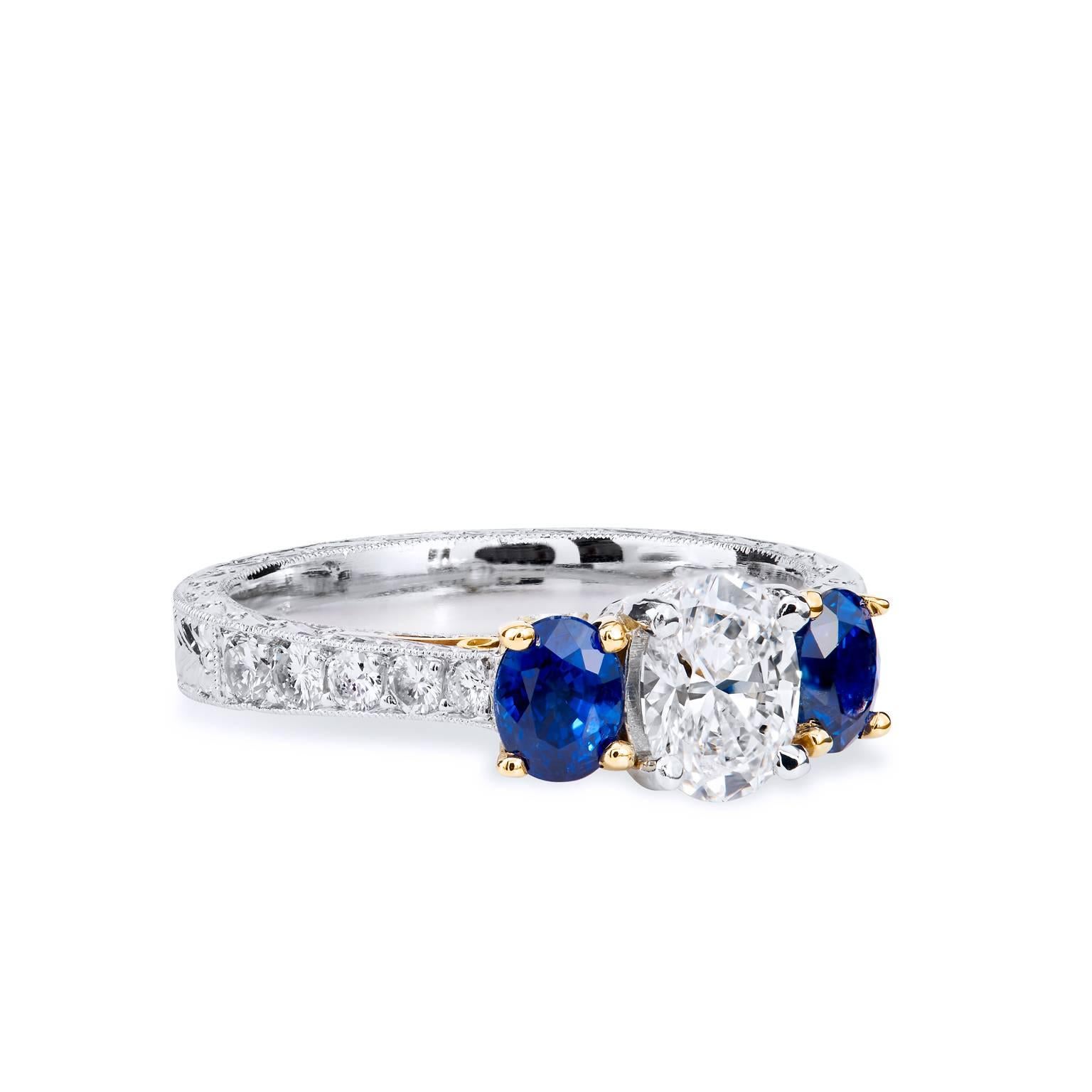 Set in platinum and 18kt yellow gold, this three stone ring showcases oval cut sapphires and diamonds, one of the hottest cuts of gemstones today. The center diamond is GIA certified and weighs .71ct D-VS1accented by two royal blue sapphires .60cts