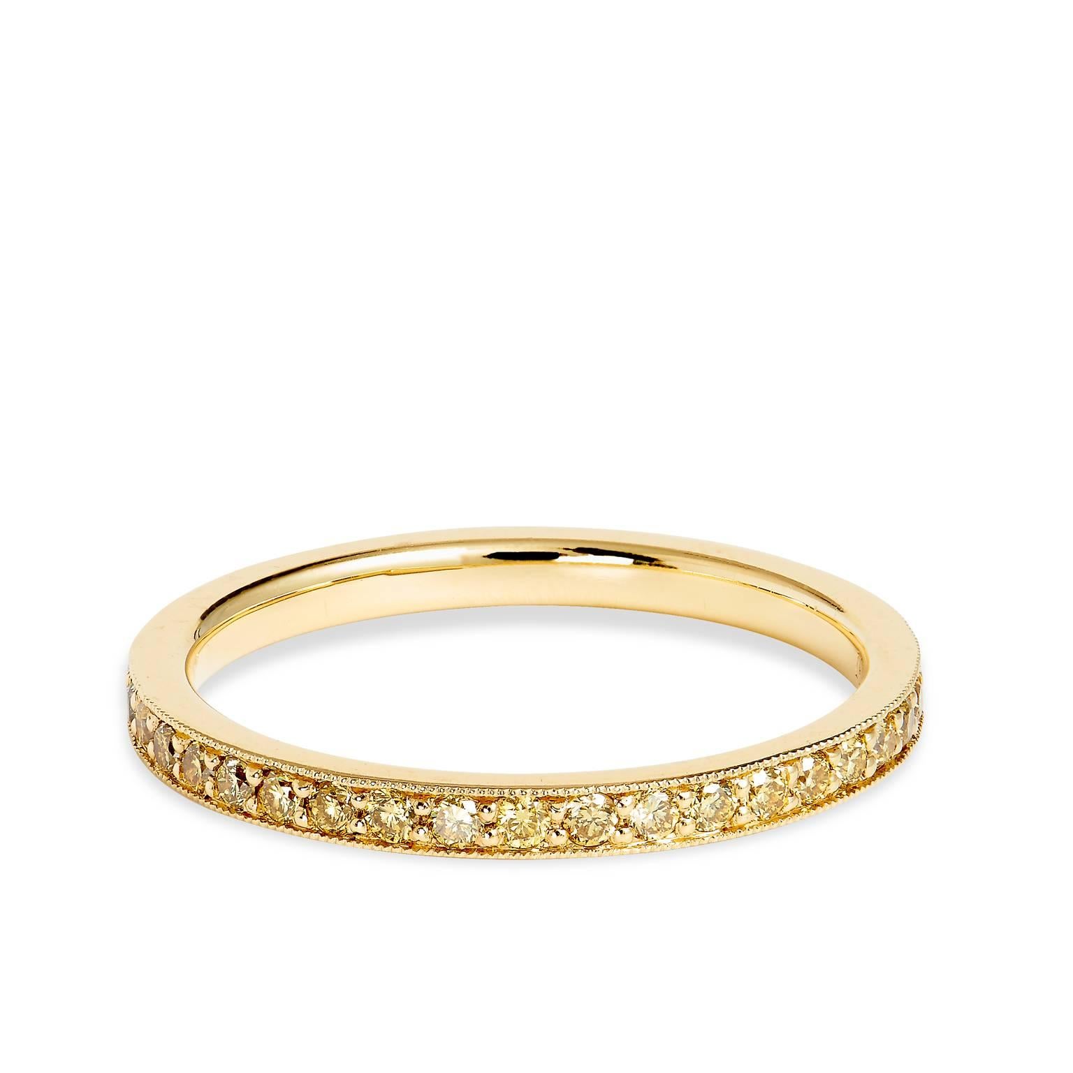 This eternity band is crafted in 18kt yellow gold with .50cts of yellow diamonds. It displays beautiful milgrain detail upon the edges of the band. It looks stunning paired with an engagement ring or even stacked with multiple bands. We have this