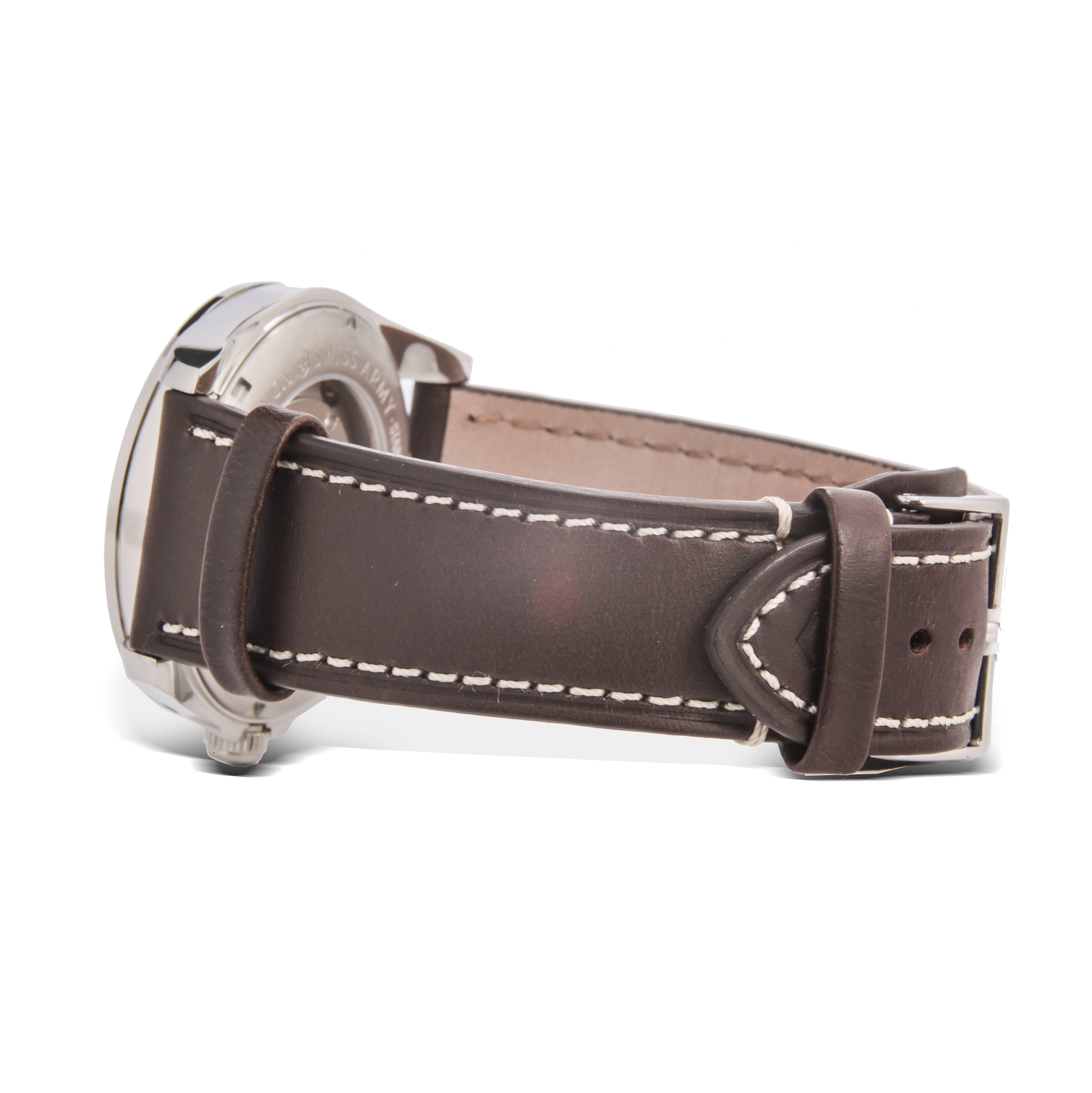 Stainless steel case with a brown leather strap. Fixed stainless steel bezel. Black dial with luminous silver-tone hands and Arabic numeral hour markers. Minute markers around the outer rim. Dial Type: Analog. Date display at the 3 o'clock position.