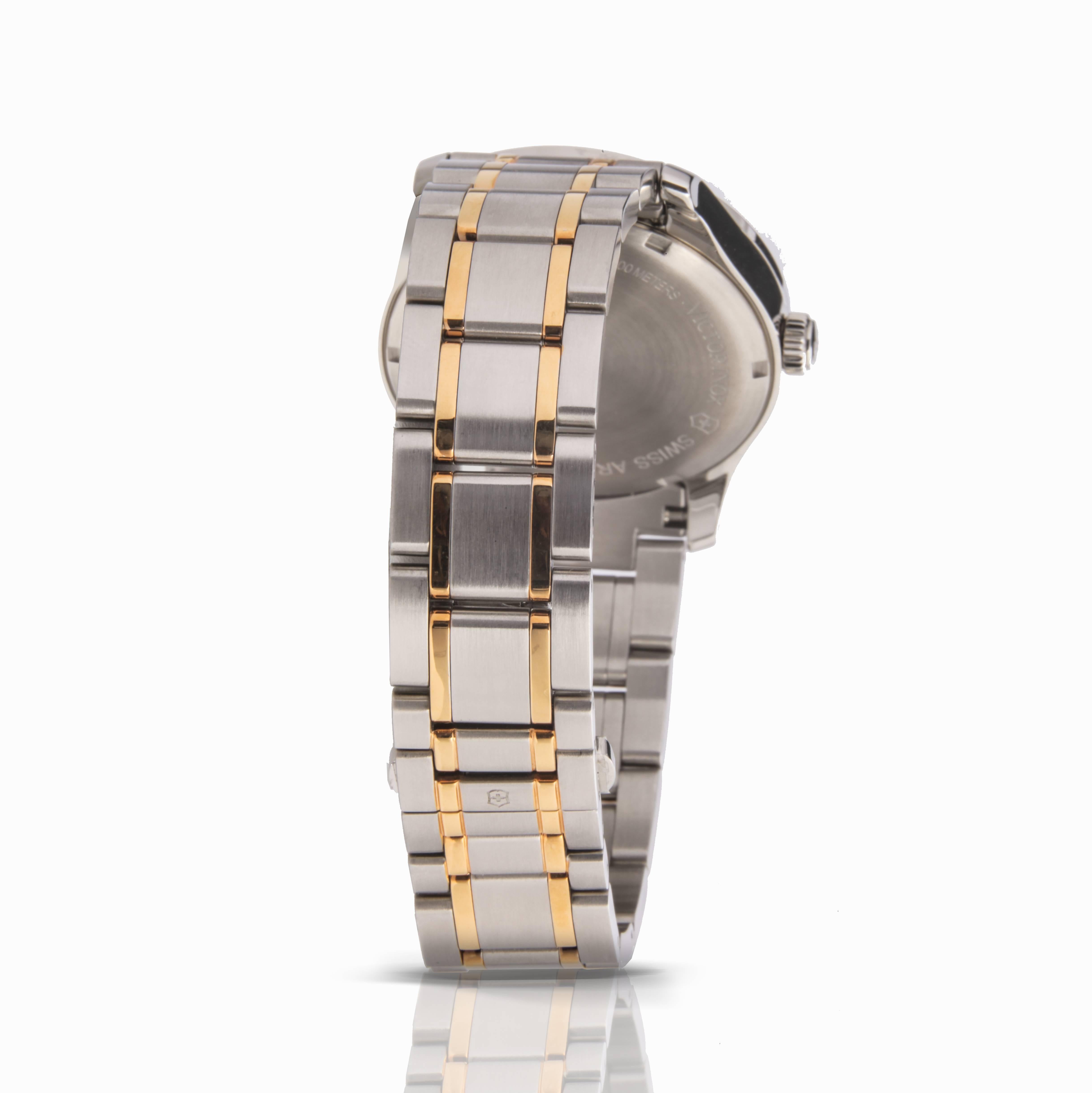Stainless steel case with a two-tone (silver and gold-tone) stainless steel. Fixed stainless steel bezel. Silvered dial with silver-tone hands and index hour markers. Arabic numerals mark the 3, 6 and 9 o'clock positions. Military time. Minute