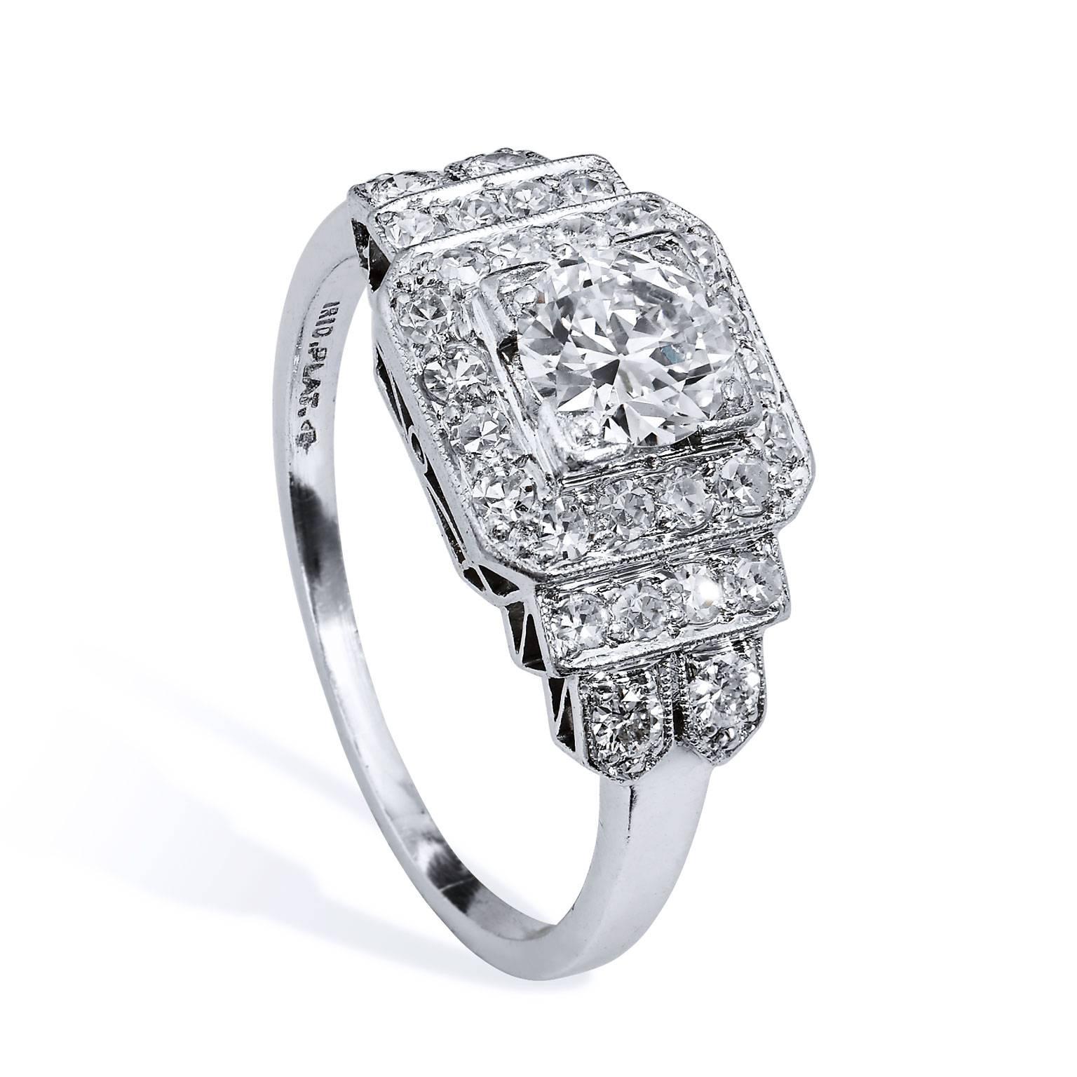 Make a timeless declaration of your love and commitment with this ornate previously loved Art Deco Iridium Platinum engagement ring. A striking 0.60 carat Old European cut diamond set at center (G/H/VS1) is encapsulated by twenty-eight pieces of