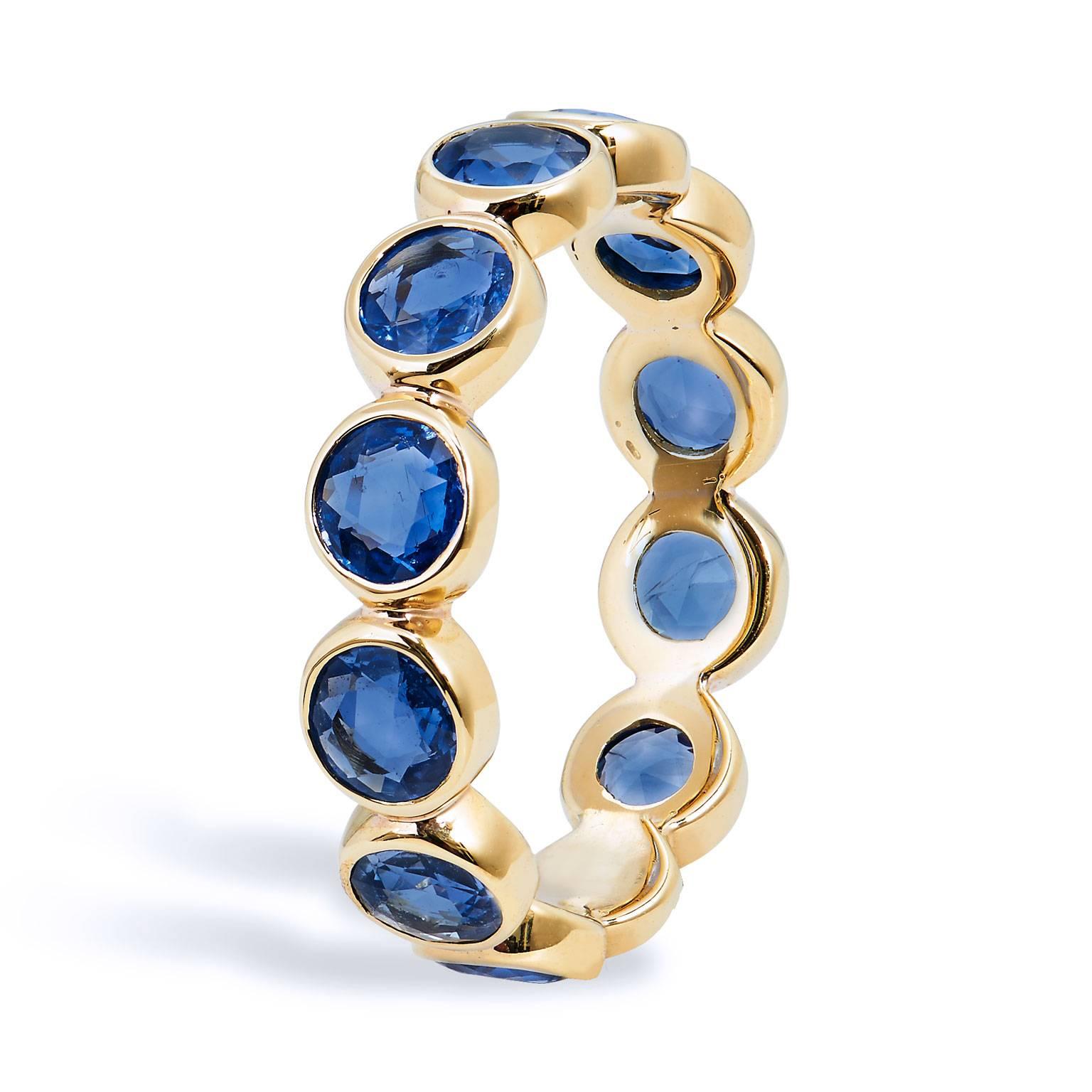 This handcrafted 18 karat yellow gold eternity band ring features twelve bezel set St. Clair Rose cut blue sapphires placed together to produce an approximate 3.00 carats of eye-catching color. This band ring stirs and illuminates the essence of her