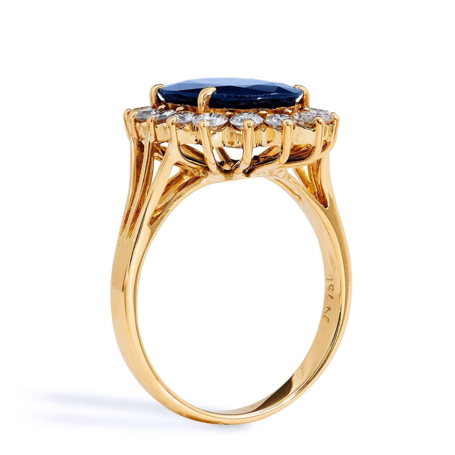 Previously loved 18 karat yellow gold ring featuring a 4.47 carat oval sapphire set at center. To further accentuate the deep sea of blue at center, sixteen round diamonds envelop the center gem with approximately 1.00 carat of sumptuous and