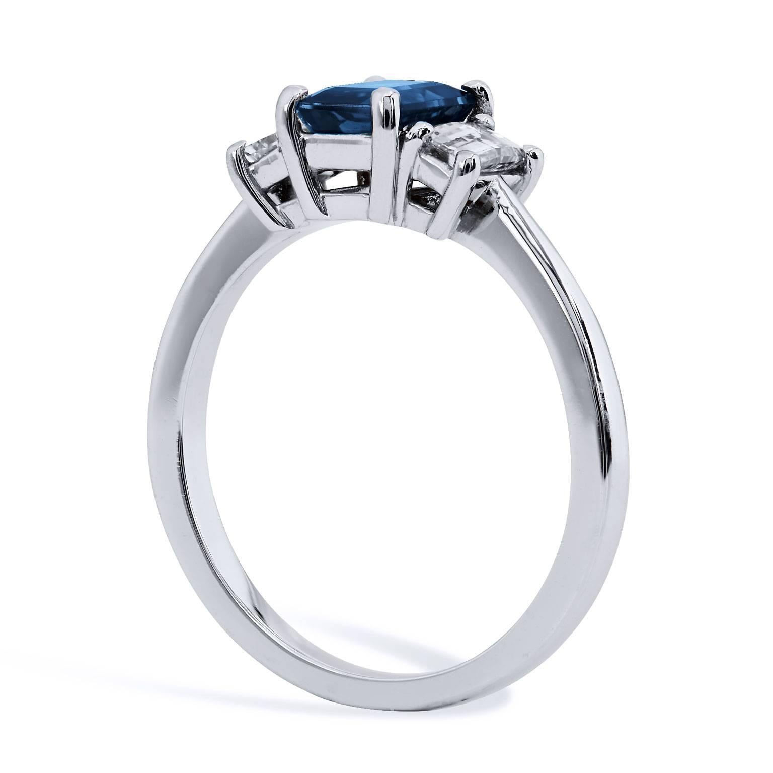 An embellished yet minimal design, this spectacular platinum ring features a 1.28 carat emerald cut blue sapphire set at center while 0.56 carat of emerald cut diamond side stones (J/k/VS2/SI1) enhance the four-prong blue sapphire- sweet and