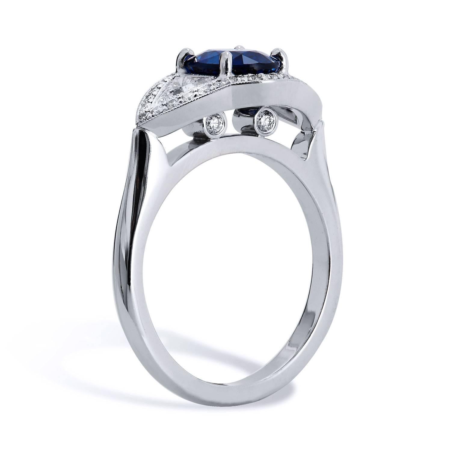 Like that of the blue evil eye of the Mediterranean, a 1.50 carat Royal Blue Sapphire is set at center in this mesmerizing handmade 18 karat white gold cocktail ring. Two bezel-set trillion cut diamonds (I/J/SI) with a total weight of 0.36 carat,