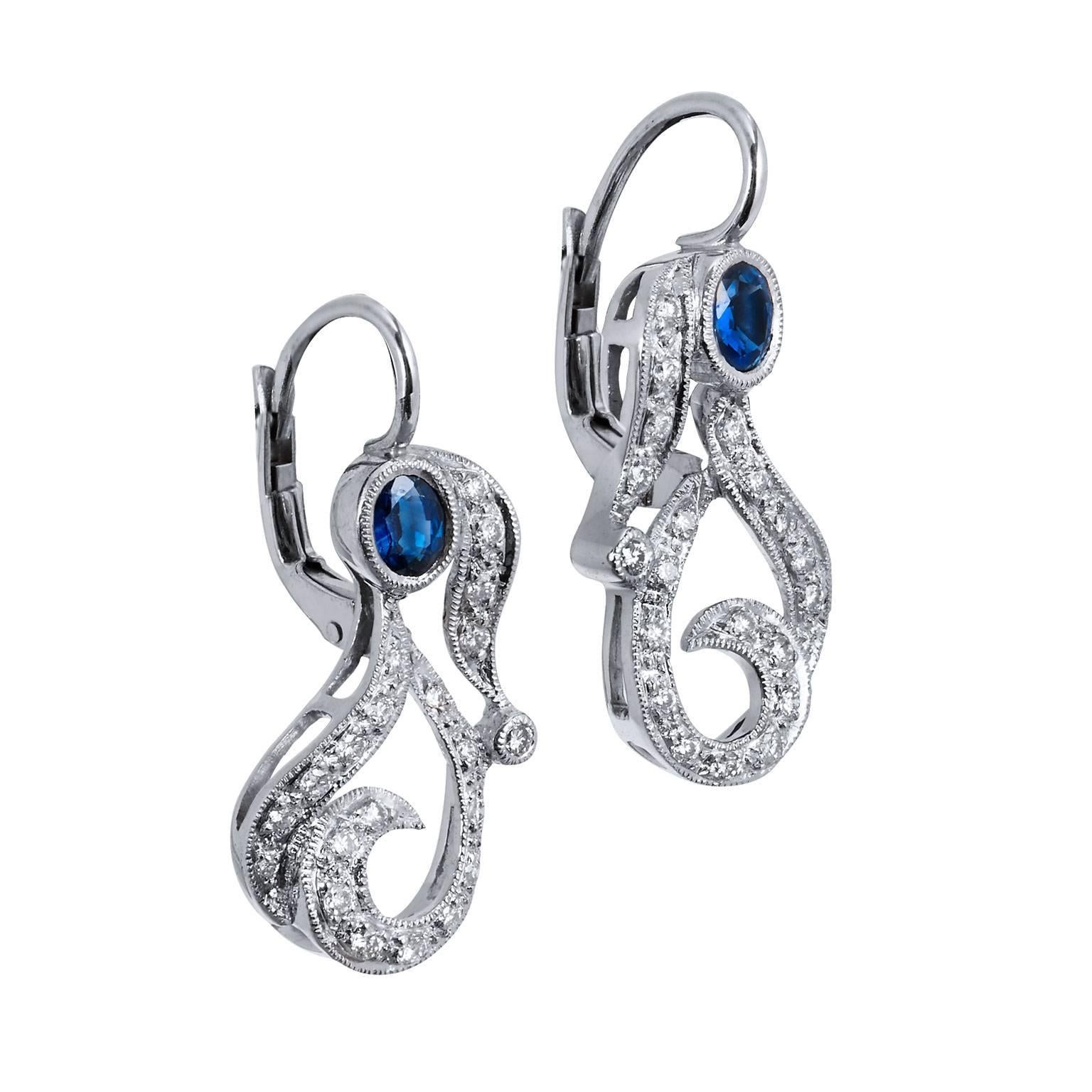 18 karat white gold fashioned in a paisley shape form the base of these previously loved lever-back earrings. Two pieces of oval sapphire with a total weight of 0.60 carat are bezel set at the bail as 0.33 carat of pave set diamond flutter in a