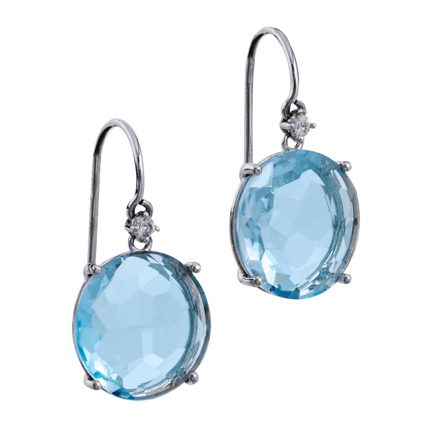 Two 12 millimeter round blue topaz are prong set and fashioned in 14 karat white gold  in these fish hook earrings. These earrings also feature 0.04 carat of pave set white sapphire on the bail.