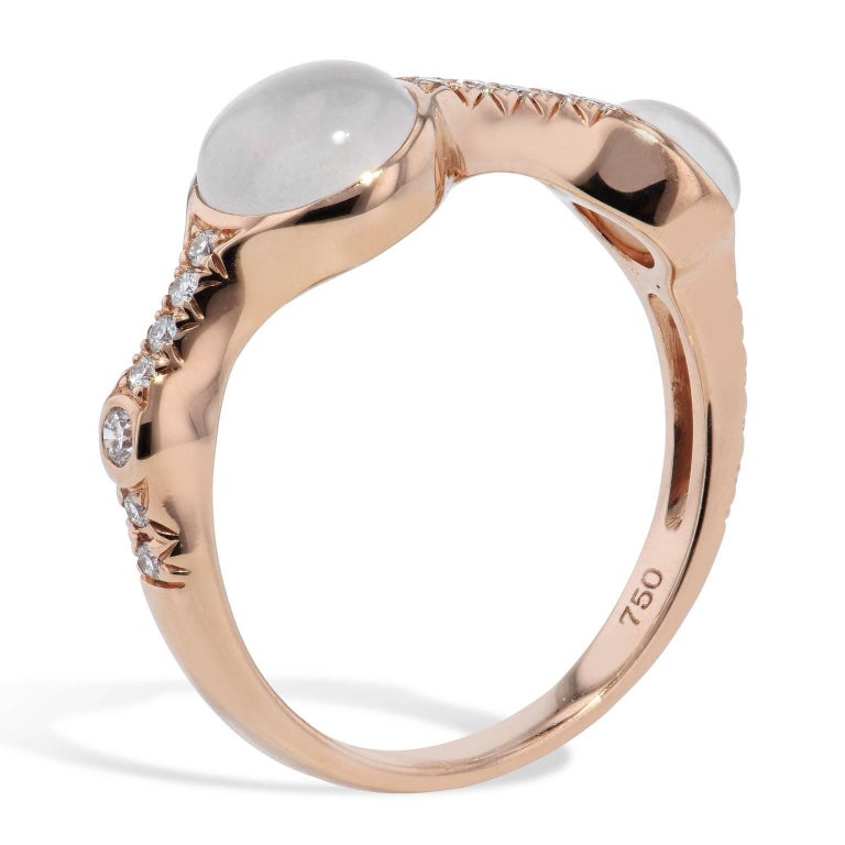 Fashioned in 18 karat rose gold, two cabochon moonstones with a total weight of 1.74 carat, are punctuated by 0.15 carat of pave-set diamond in this band ring.