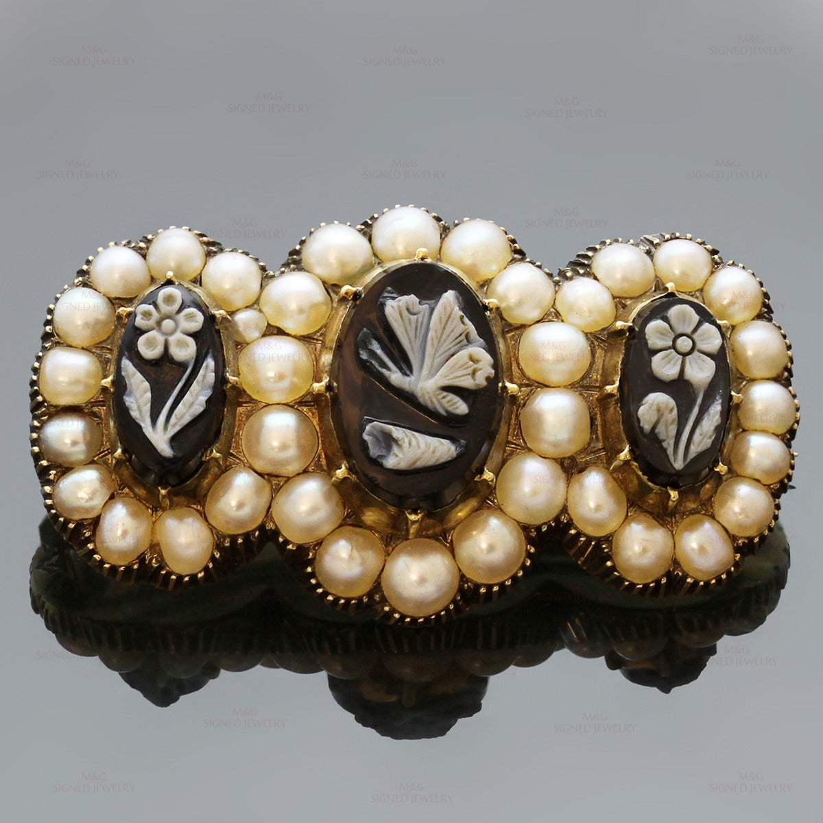 This exquisite hand-made antique circa 1855 brooch is made in 14k yellow gold and set with three black oval agate stones decorated with a butterfly and floral cameo motifs and encircled with saltwater cultured pearls. Engraved in the back 'To my