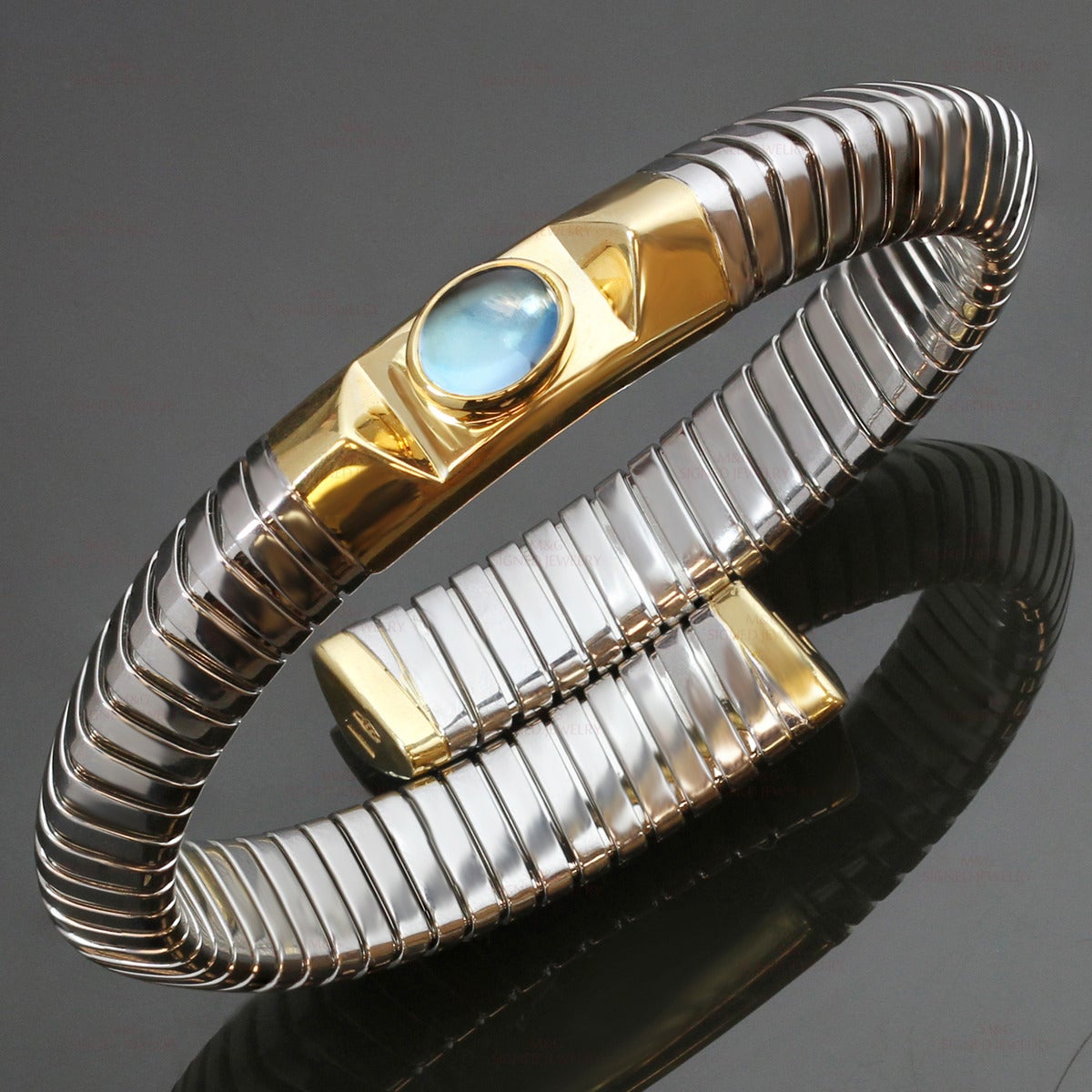 This iconic Bvlgari Tubogas bangle bracelet is made in stainless steel and features an oval cabochon blue topaz stone set in 18k yellow gold. Made in Italy circa 1990s. Measurements: 0.38