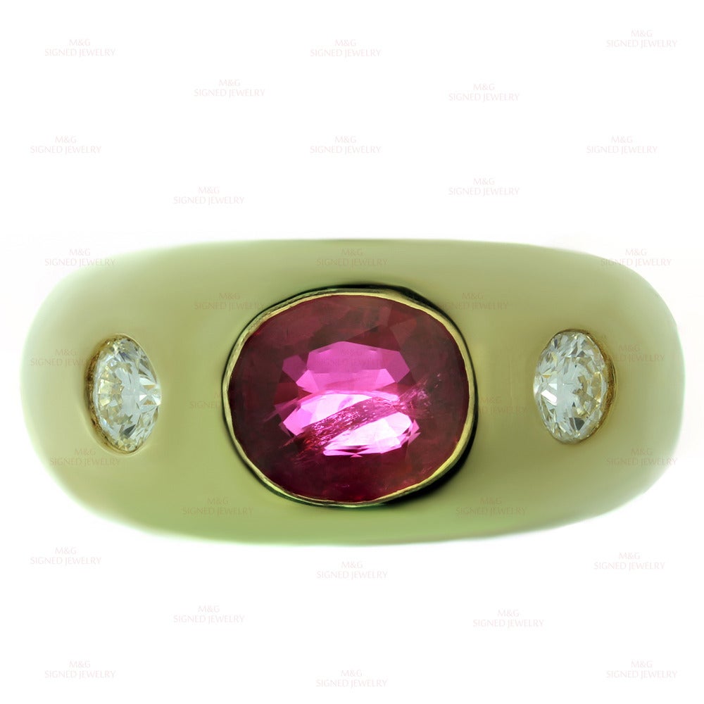 This stunning gypsy ring is made in 18k yellow gold and bezel-set with 2 round brilliant-cut F-G VS1-VS2 diamonds of an estimated 0.50 carats and a bright sparkling eye-clean faceted oval red ruby measuring 3.9mm x 7.8mm x 9.9mm. The ruby has not