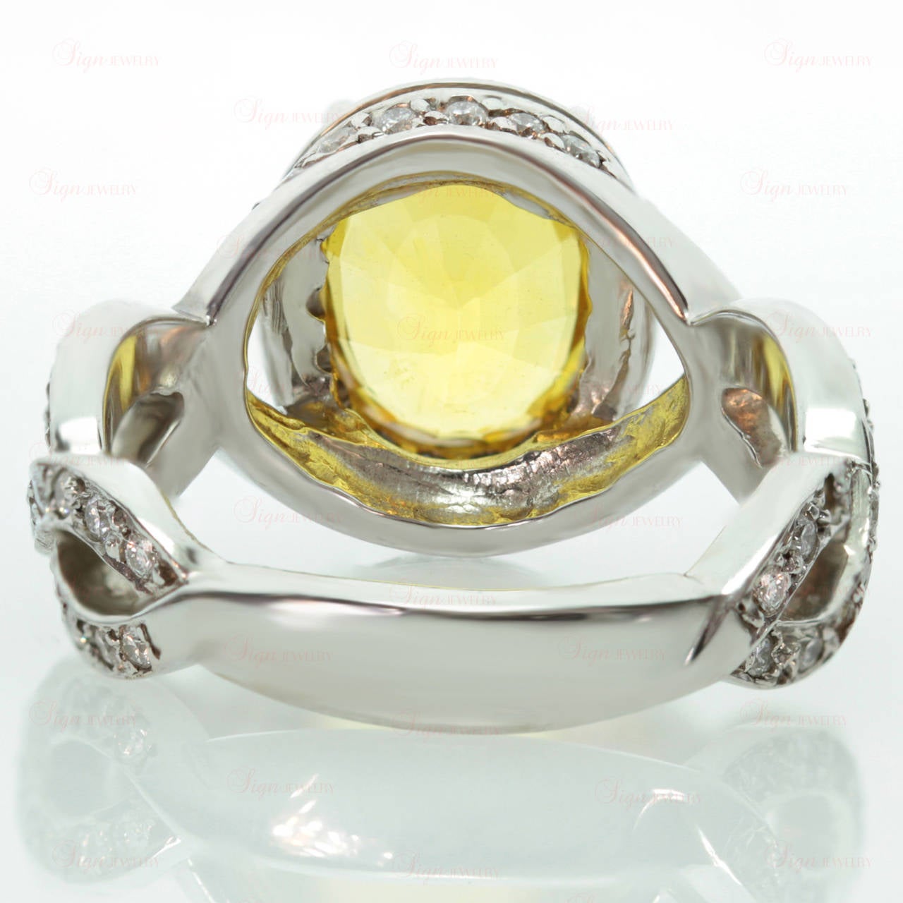 This modern women's cocktail ring is made in 18k white gold and features a natural 3 carat faceted 7.0mm x 10.0mm oval yellow sapphire completed by an estimated 1.25 carats of sparkling pave-set round diamonds. A radiant design. Measurements: 0.43