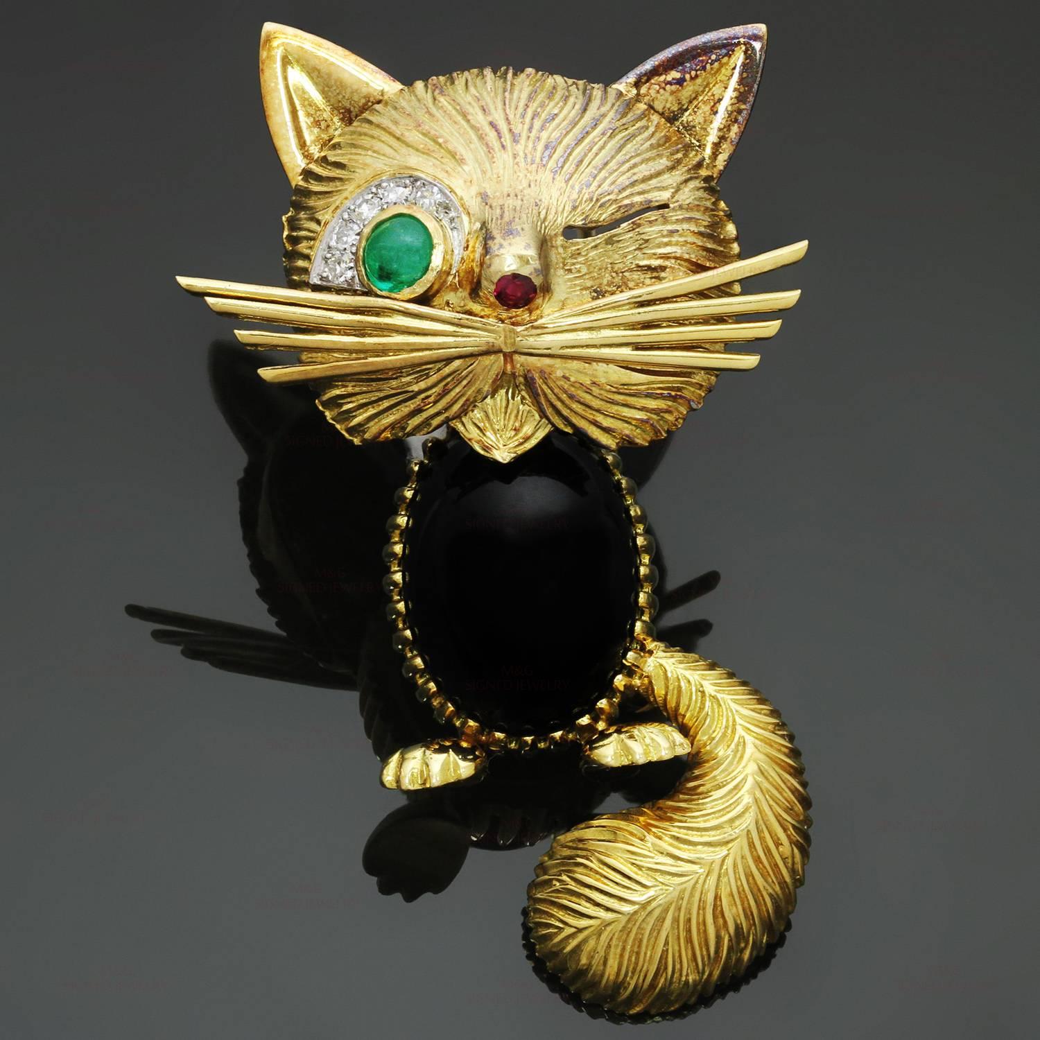 This rare and fabulous Van Cleef & Arpels brooch features an iconic Chat Malicieux/Winking Cat design crafted 18k textured yellow gold and decorated with a green emerald eye accented with sparkling diamonds, a ruby-set nose, and an oval cabochon