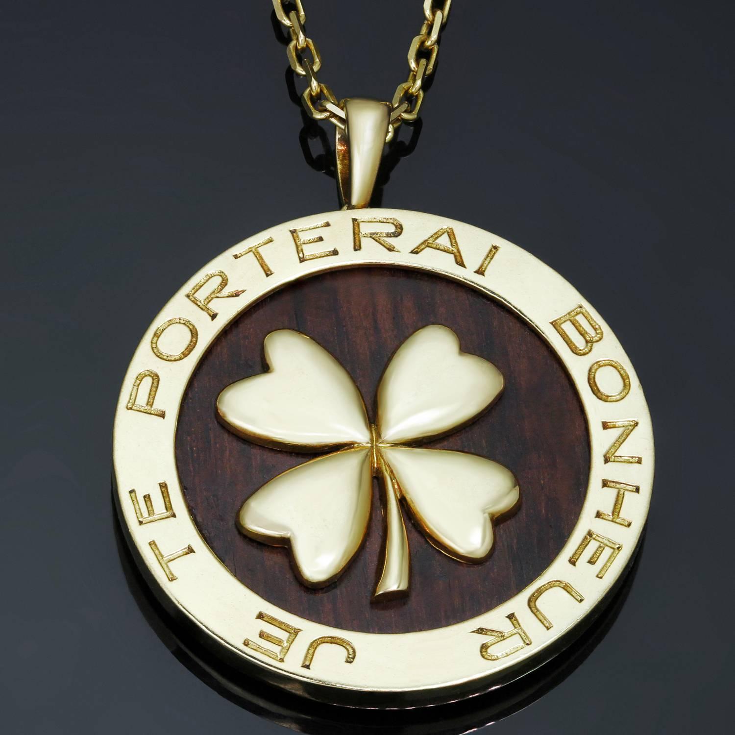 This rare Van Cleef & Arpels necklace is crafted in 18k yellow gold and features a round wooden bois d'amourette pendant accented with a four-leaf lucky clover and encircled with a text 'Je Te Porterai Bonheur' for 'I Will Bring You Luck'. Signed