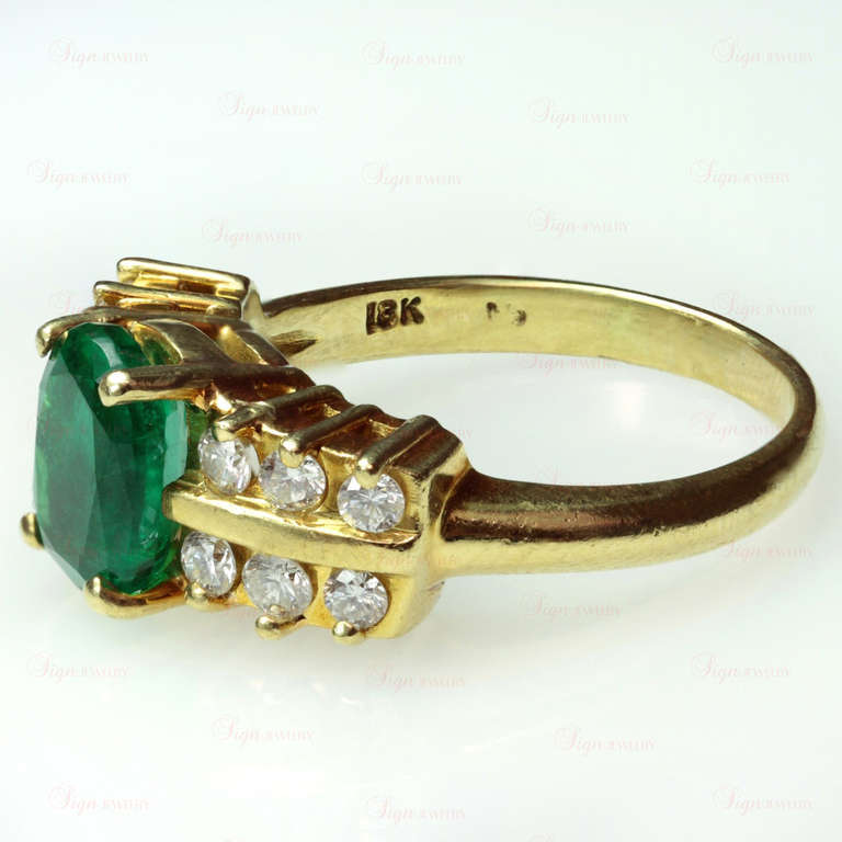A beautiful and classic 1980s Fortunoff ring made in 18k yellow gold and set with a gorgeously bright 7.0mm x 9.0mm oval emerald crown of approximately 2 carats. Accented by 12 natural round G-H VS2-SI1 diamonds of an estimated 0.55 carats.