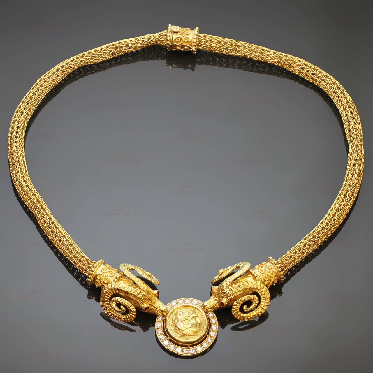 This magnificent and intricately-decorated  necklace is made in 18k yellow gold and features 2 horned ram heads with red ruby eyes of an estimated 0.24 carats and holding a round frame accented with brilliant-cut round E-F VVS2-VS1 diamonds of an