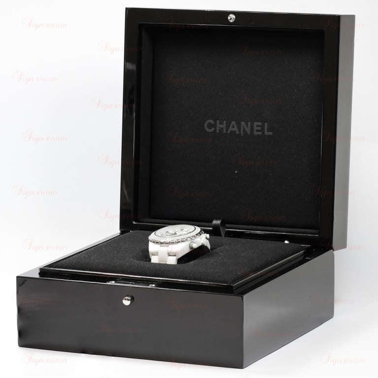 This elegant Chanel J12 watch features a scratch-resistant high gloss white ceramic case with a white ceramic bracelet, a stainless steel bezel set with an estimated 2 carats of diamonds, a white dial with luminous hands and Arabic numerals,