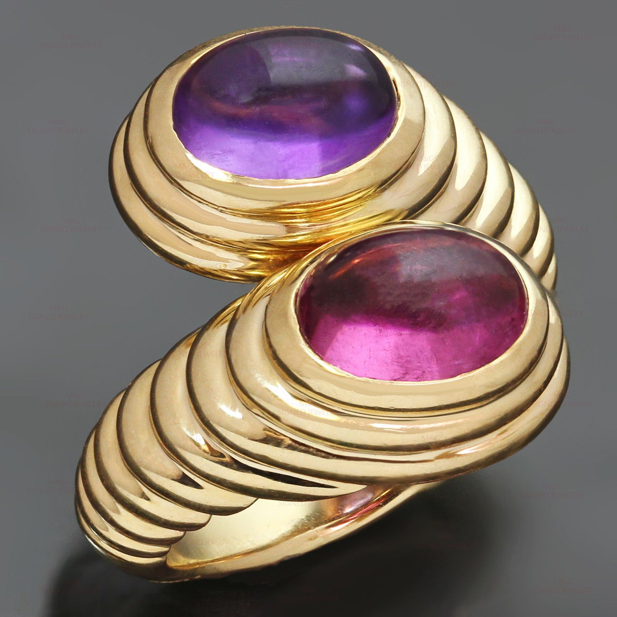 This chic Bvlgari ring is crafted in 18k yellow gold and beautifully set with two oval cabochon gemstones, amethyst and rubellite, weighing an estimated 5.0 carats. Made in Italy circa 2000s. Measurements: 0.78" (20mm) width. The ring size is