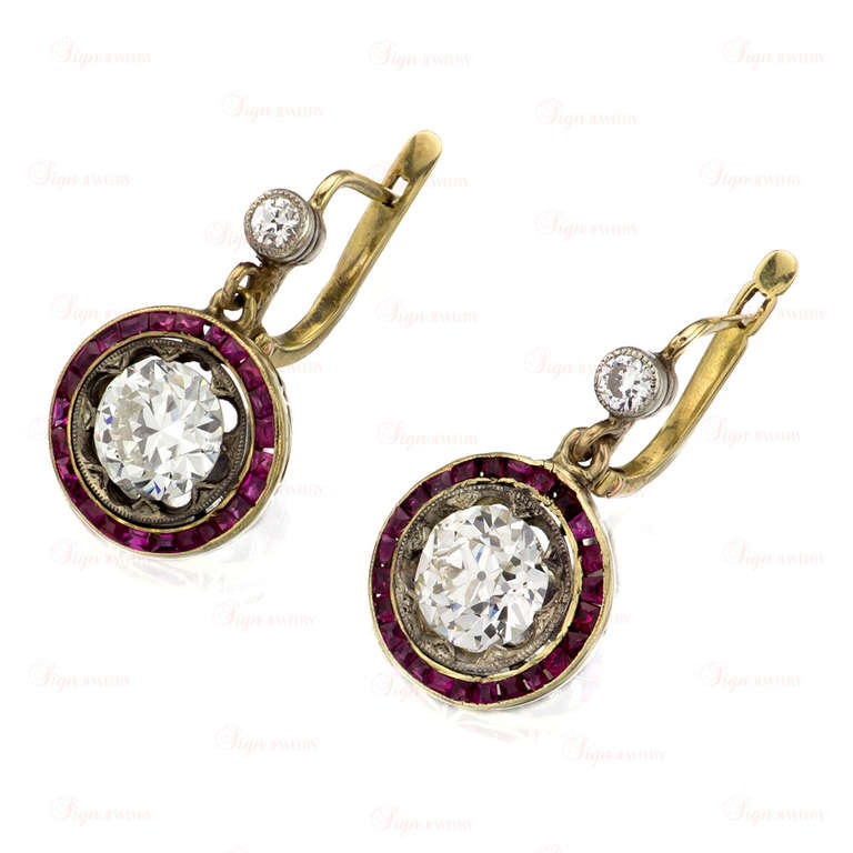 A rare Belle Epoque drop earrings featuring natural round old-mine diamond center stones - weighing 1.71 and 1.78 carats respectively. Framed by bezel-set and calibre-cut pink 1mm rubies and mounted in 18k yellow gold and platinum. Simply stunning!